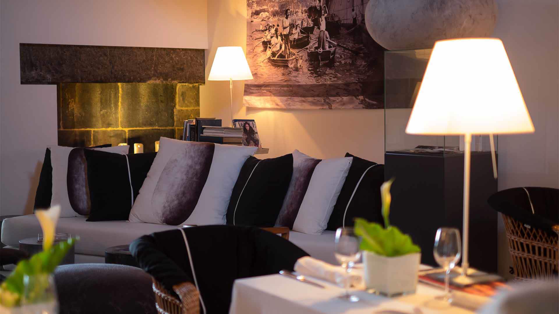 Sofá com várias almofadas e candeeiro aceso.