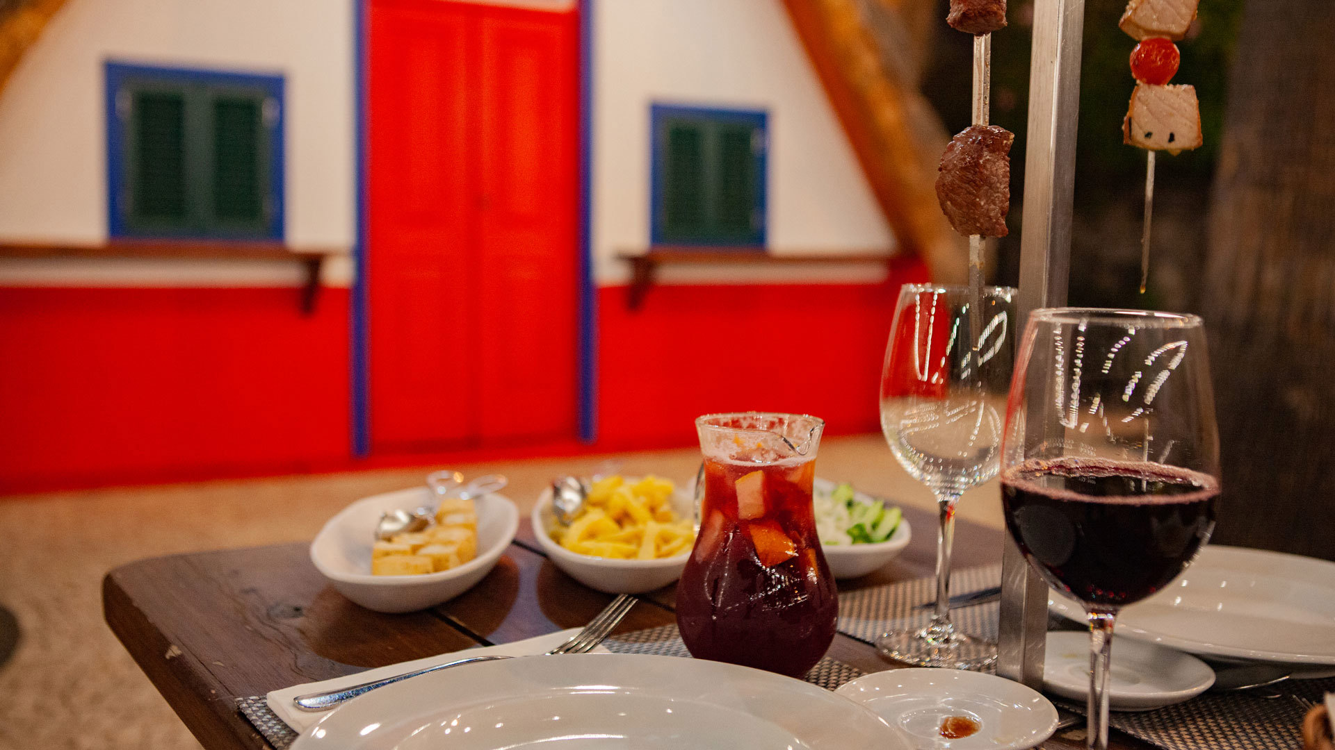 Table avec nourriture et pichet de sangria, verres servis et frites.