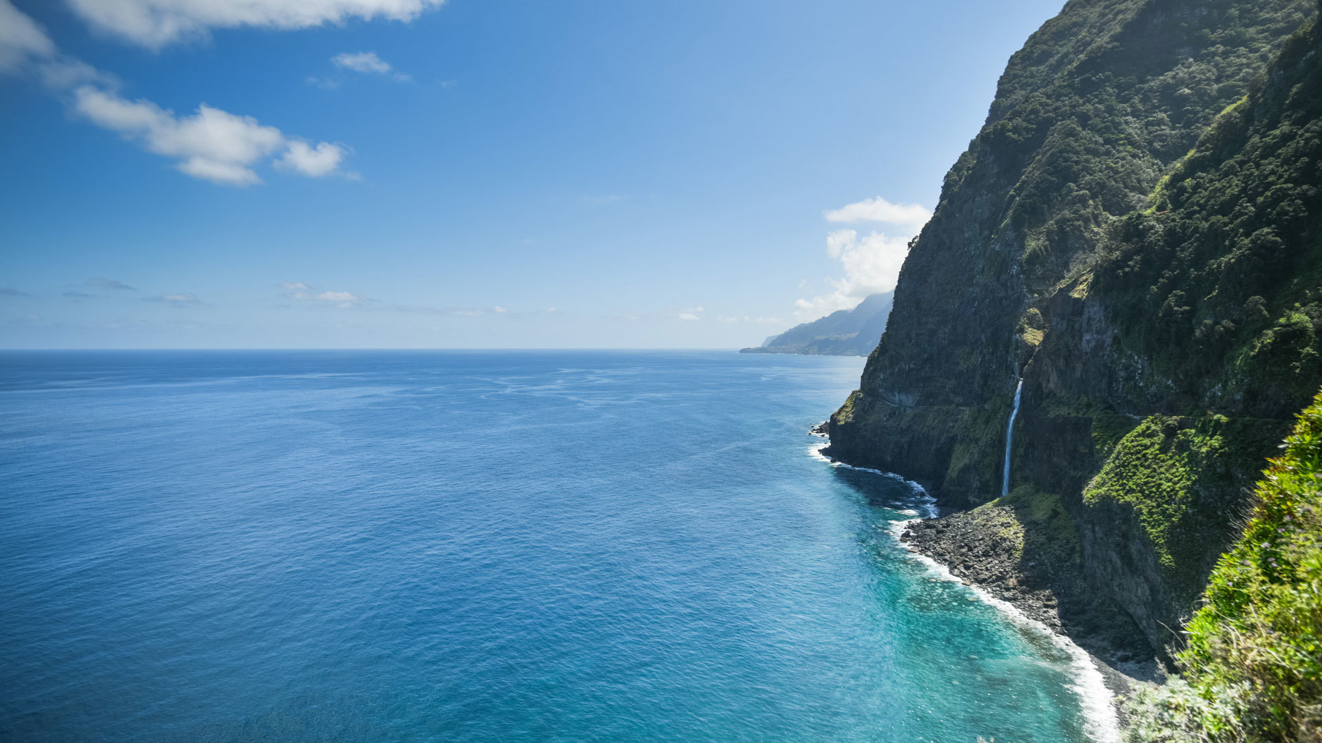 Viewpoint with waterfall, mountain, and sea in Madeira landscape.