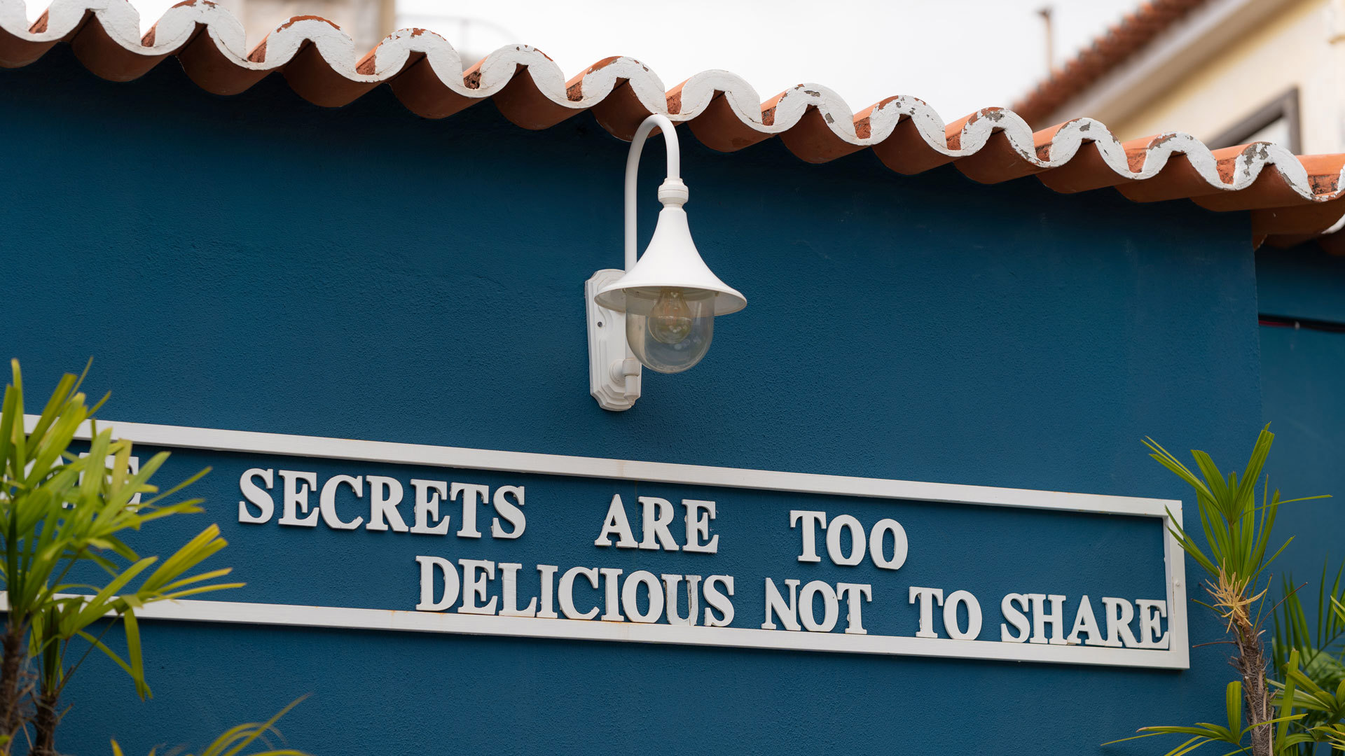 Parede azul com telhado, mensagem escrita e candeeiro.