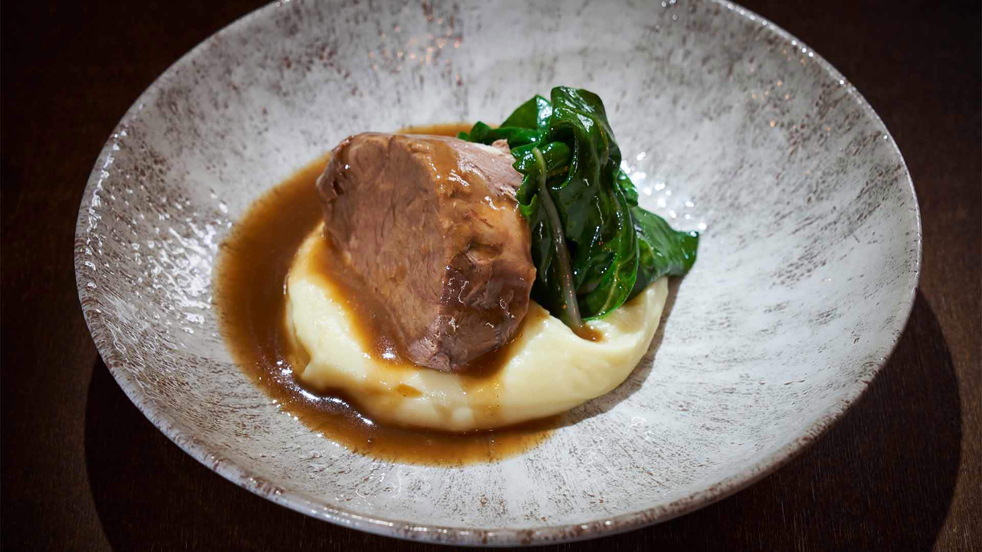 Prato com purê de batata, bife por cima e couve.