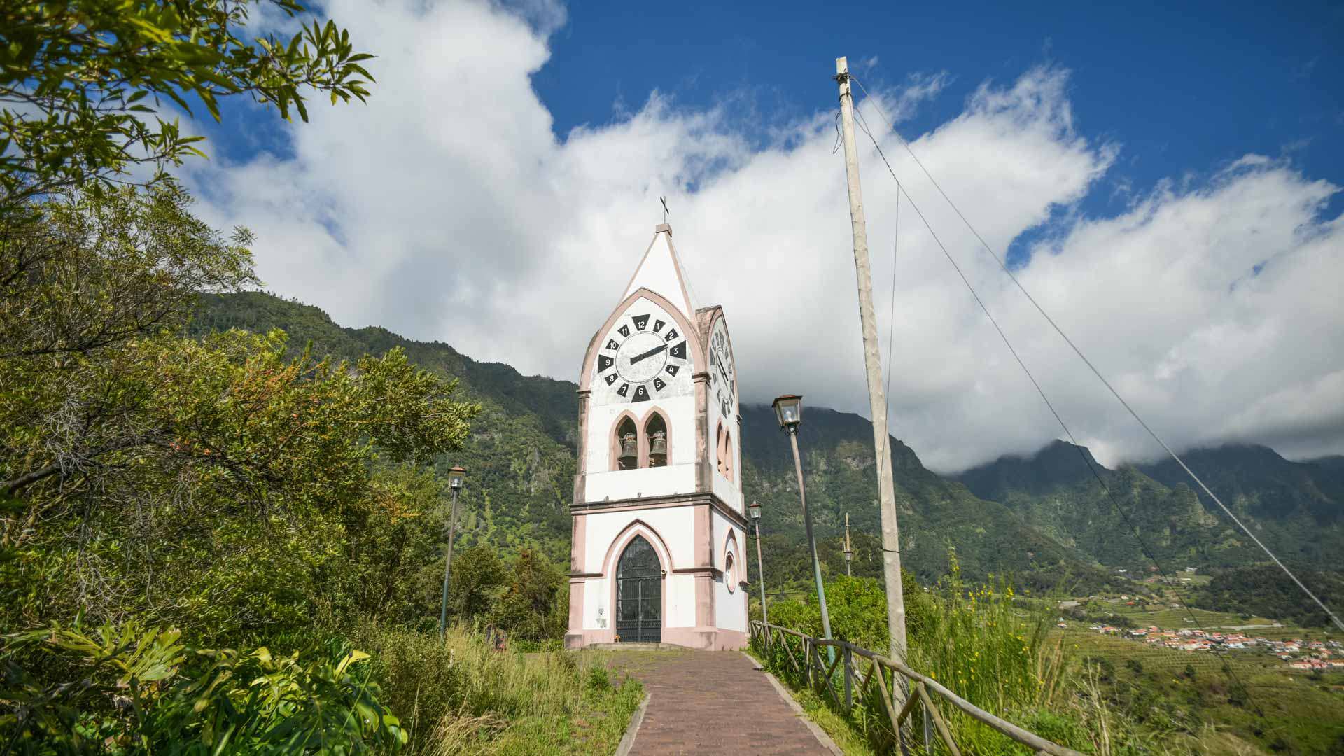 Church with mountain backdrop under cloudy sky.