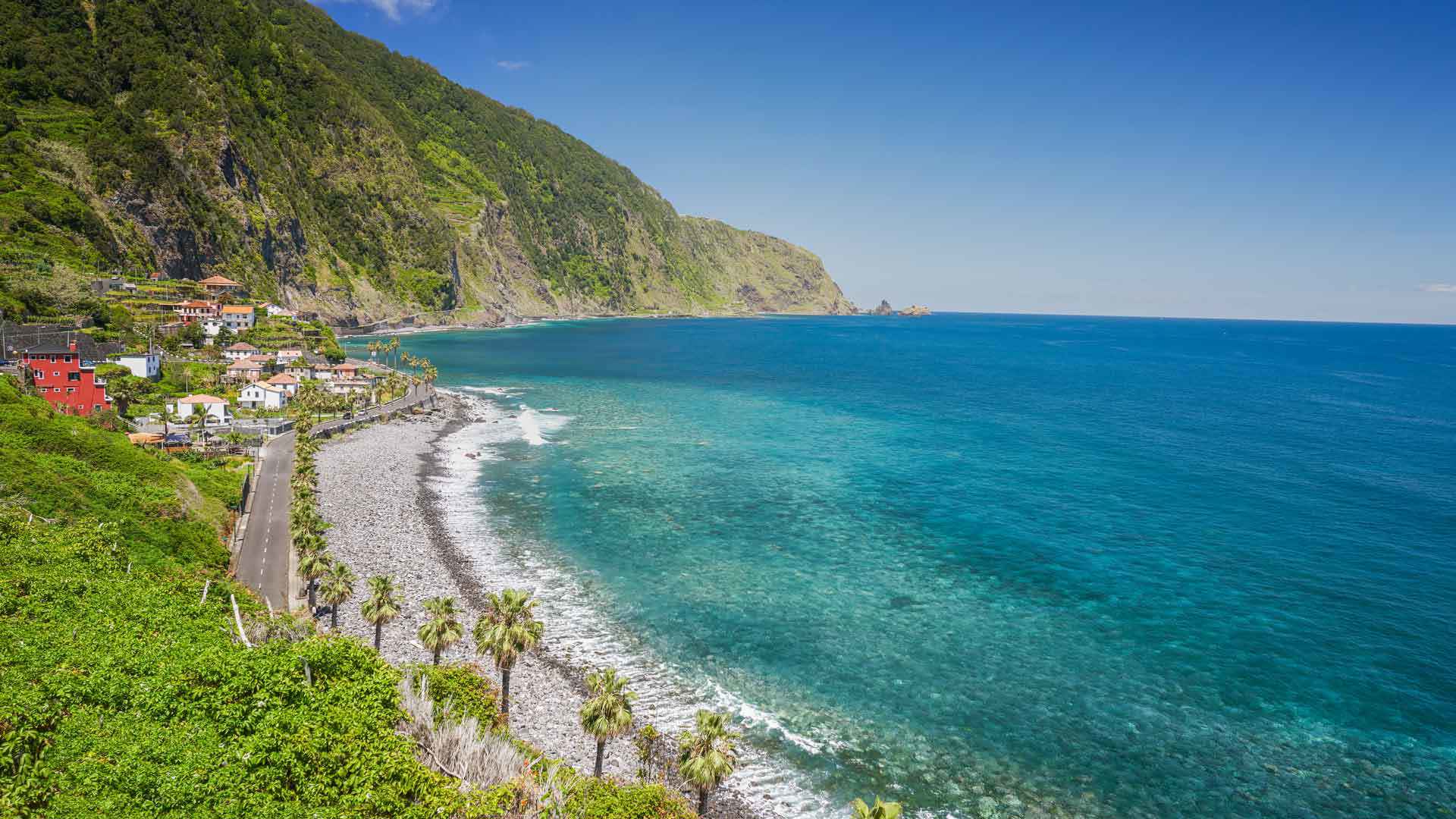 Kieselstrand am Meer mit Berg und grünem Hang auf Madeira.