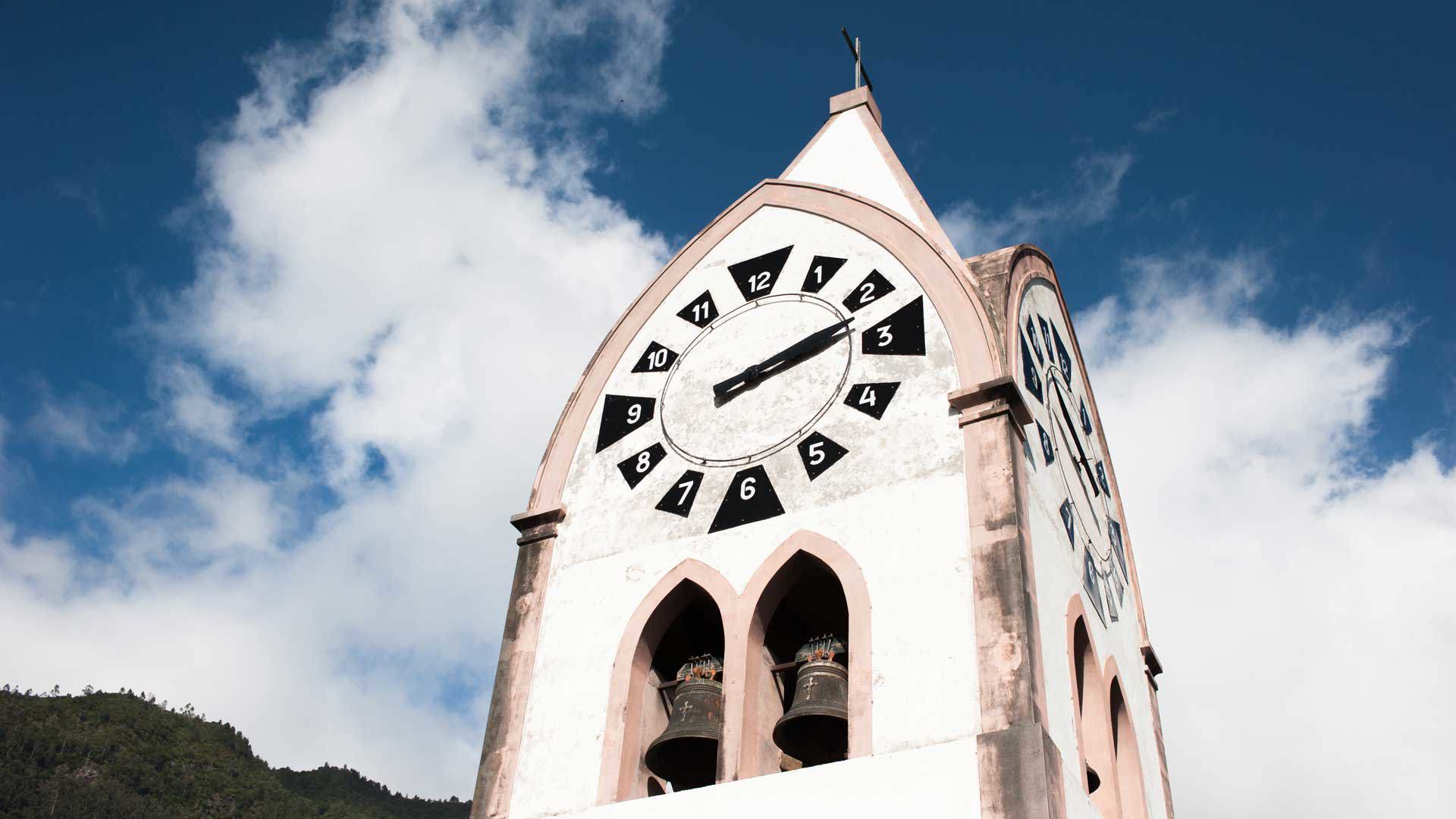 Church clock tower under blue sky with clouds.