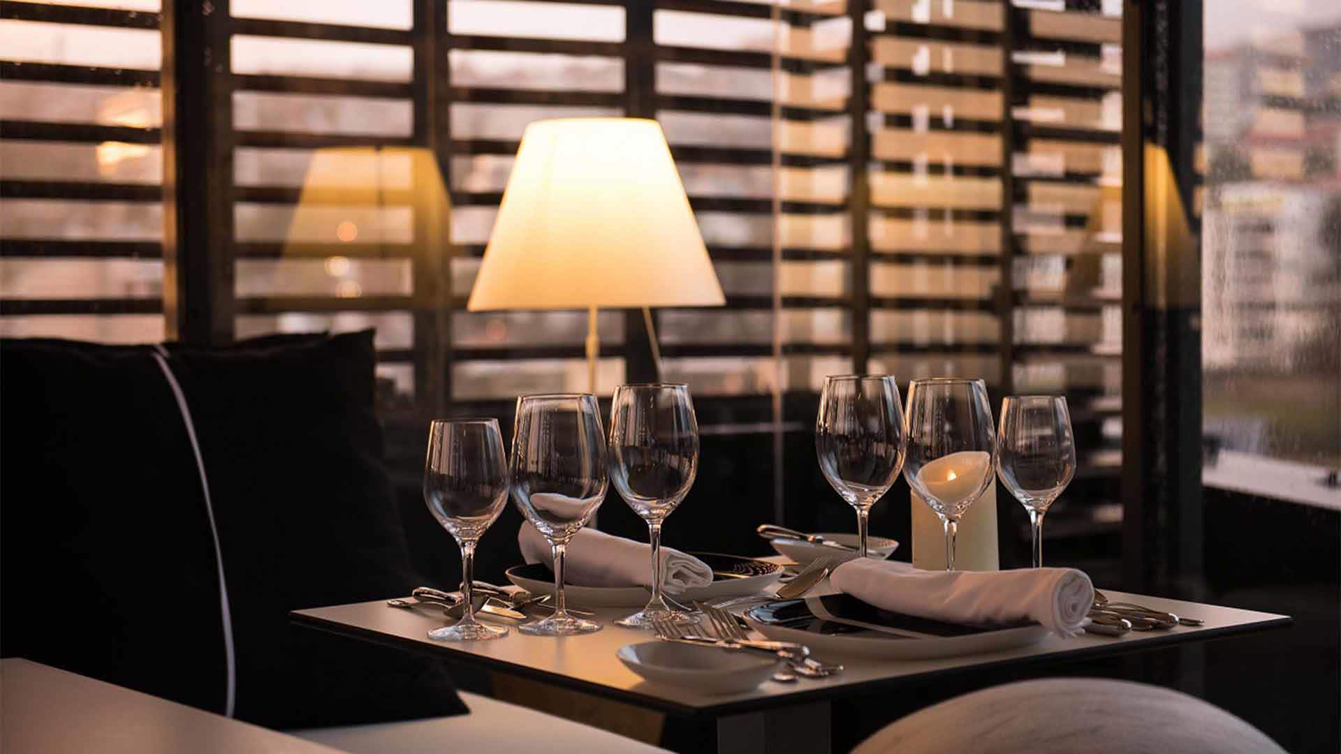 Mesa com candeeiro aceso e seis copos de vinho.