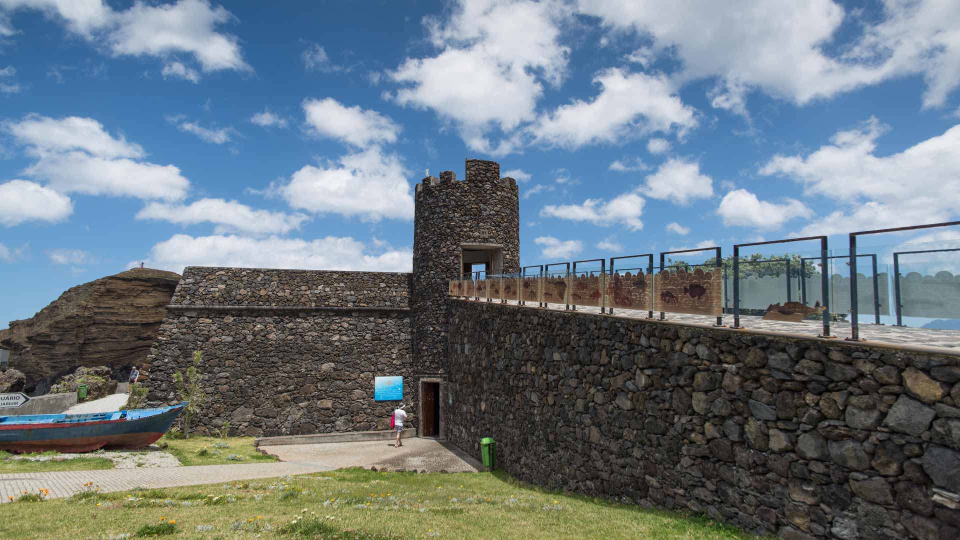 Stone fortress with bridge and people entering.