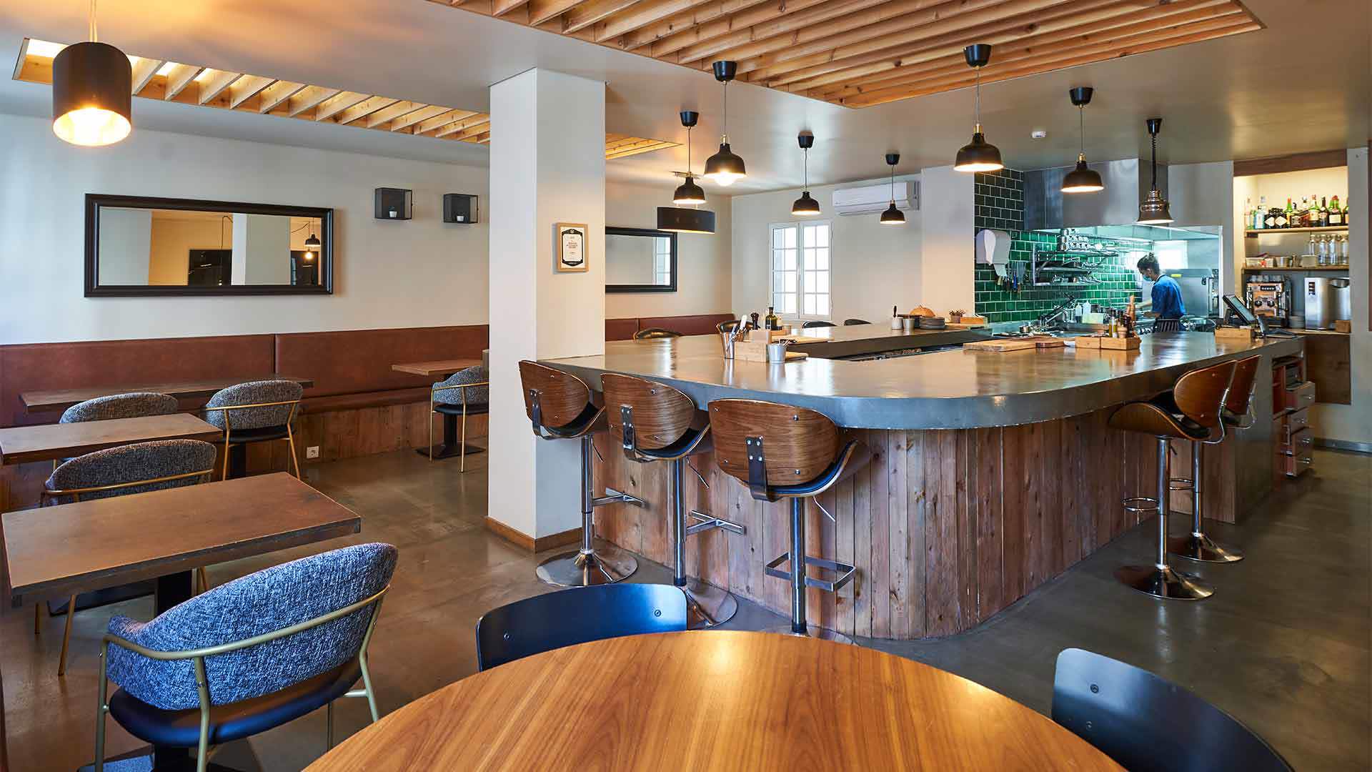 Balcão com cadeiras, mesas e luzes no teto.