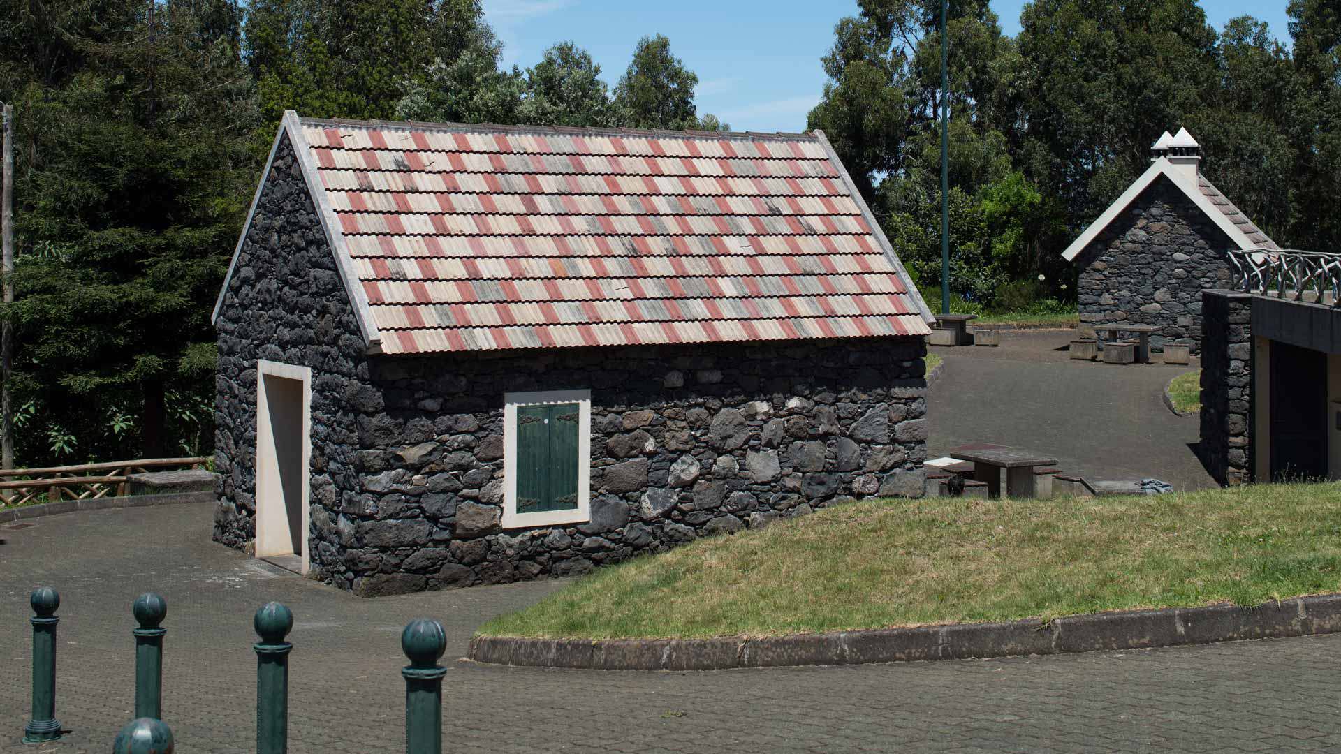 Steinhaus mit traditionellem Dach, umgeben von Natur.