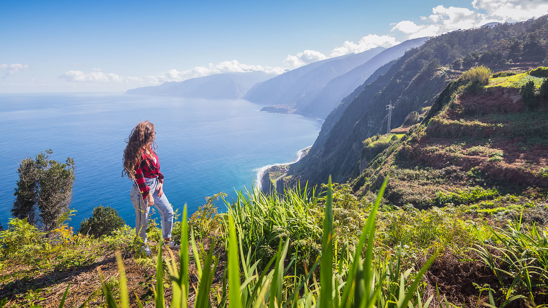 Woman at viewpoint enjoying the view of coast, sea, and mountain in Madeira.