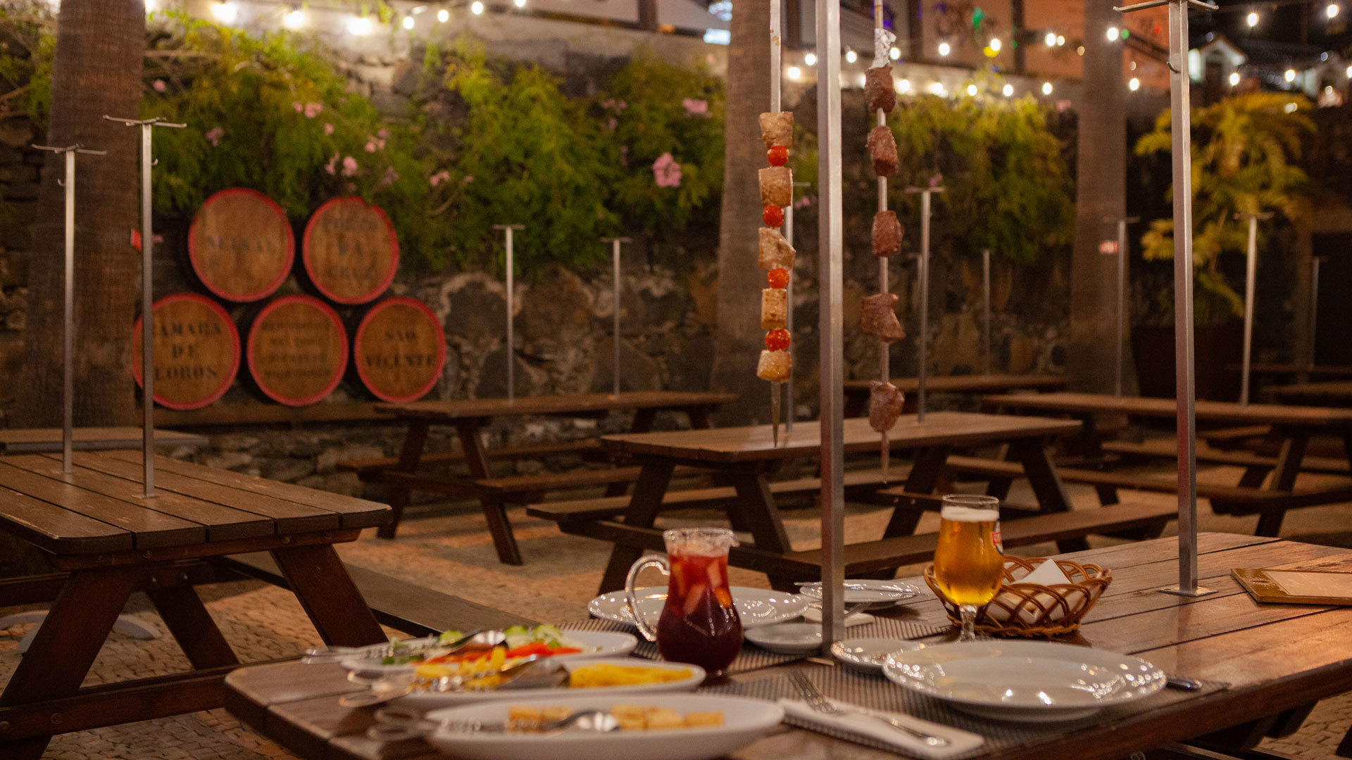 Tisch mit Spießen, Krügen mit Getränken und Tellern mit Essen.