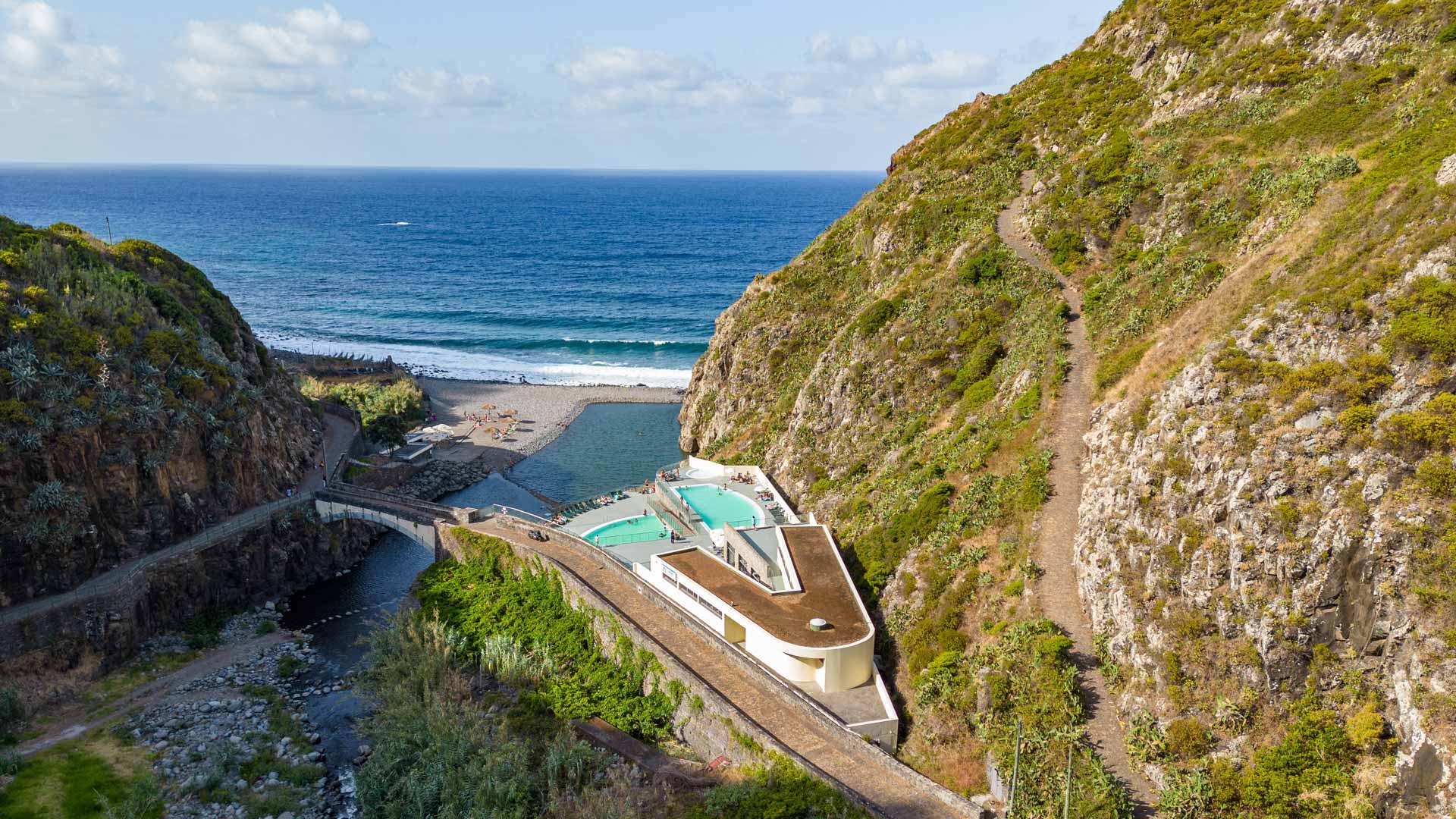 Camino en la montaña con vistas a piscinas y mar en Madeira.