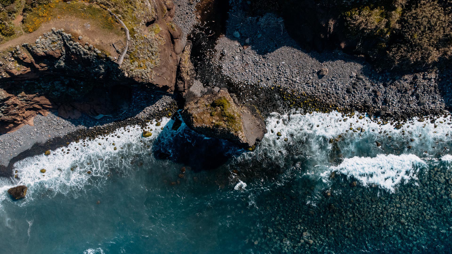 Mar com ondas na praia de calhau na Madeira.