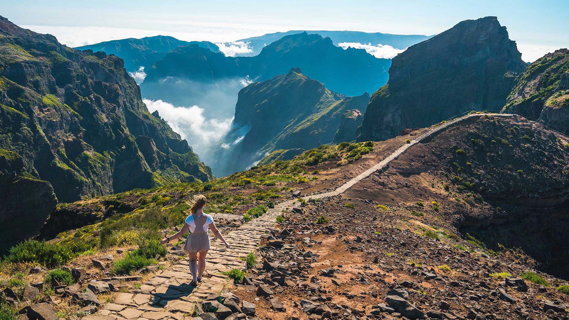 Frau wandert auf einem Pfad in den Bergen mit Wolken auf Madeira.