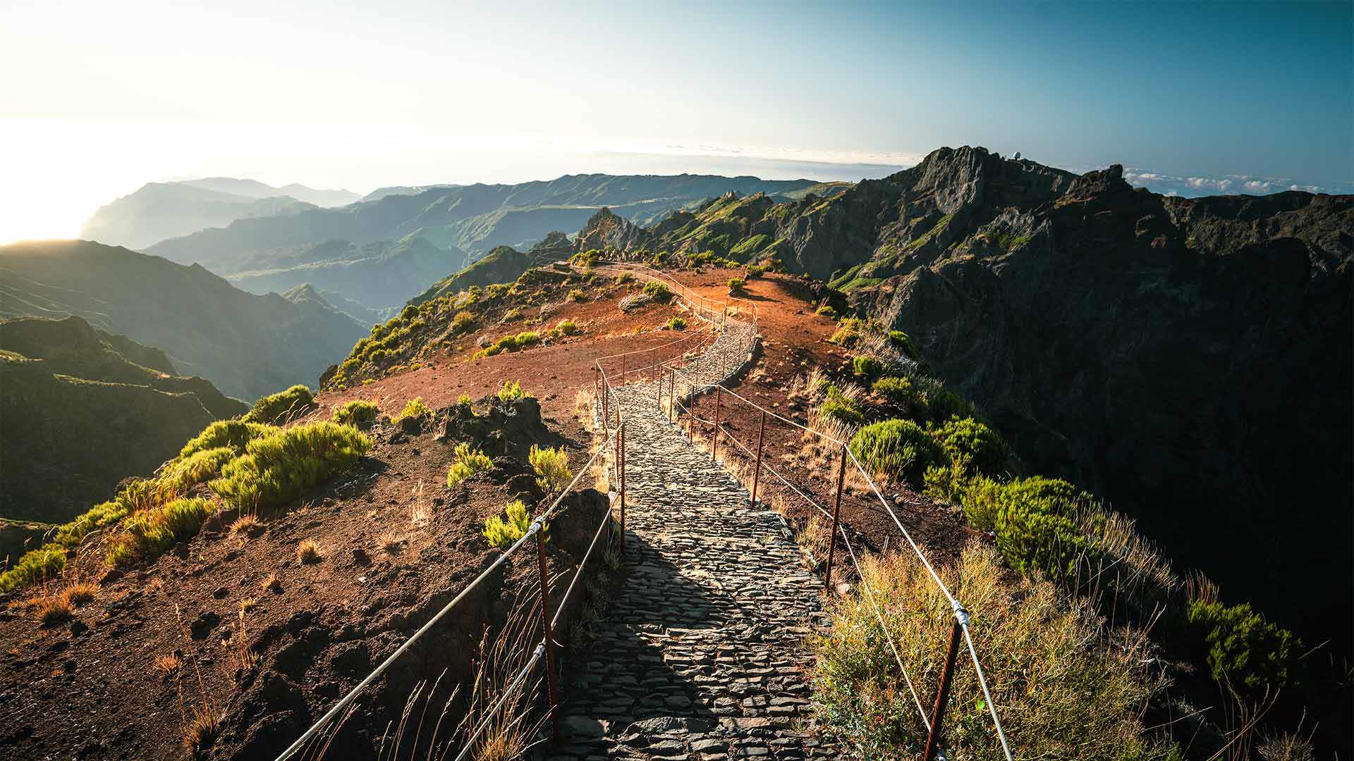 Mountain trail with sun rays illuminating Madeira’s landscape.