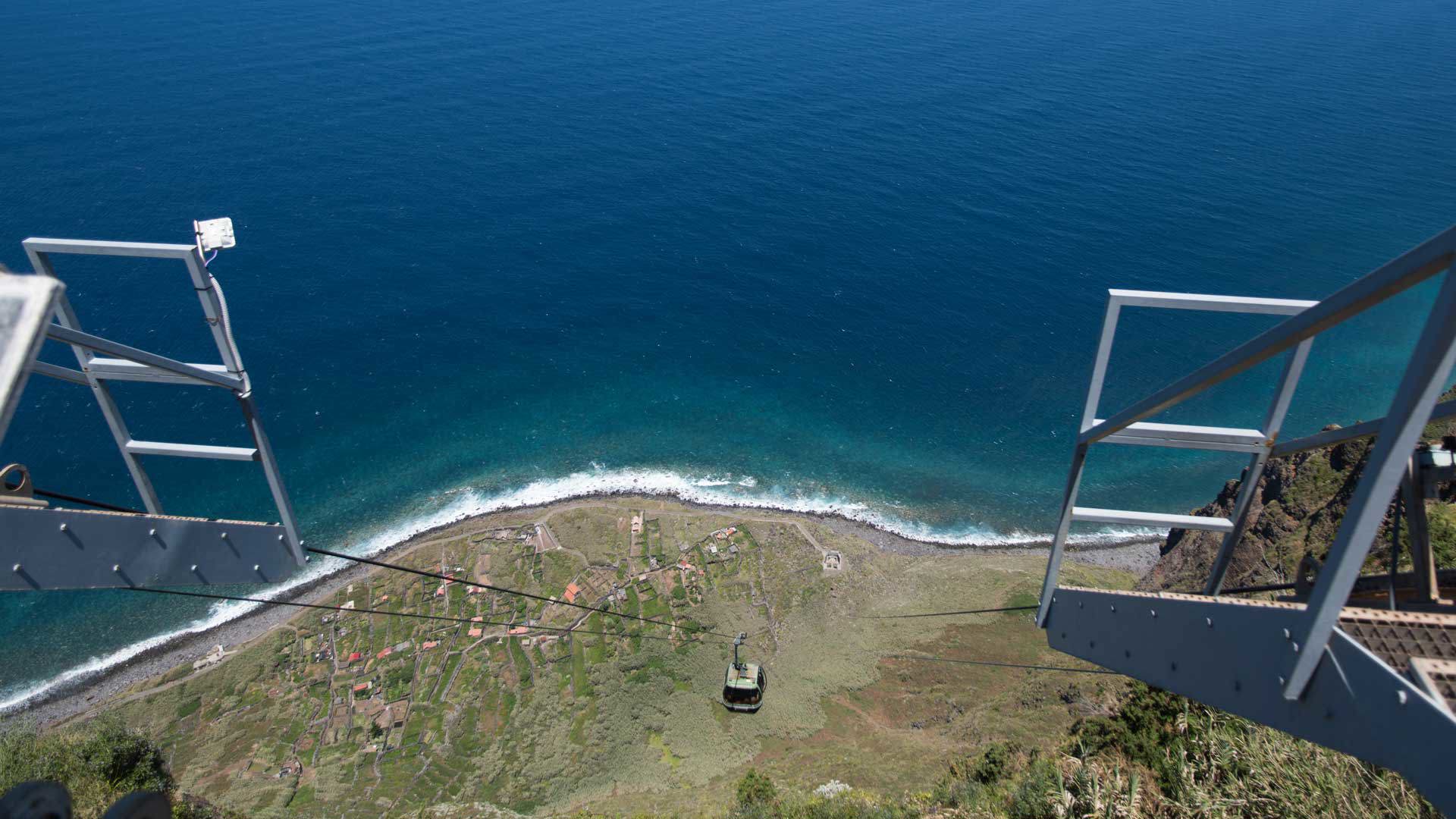Teleférico desciende por la ladera hacia el mar.