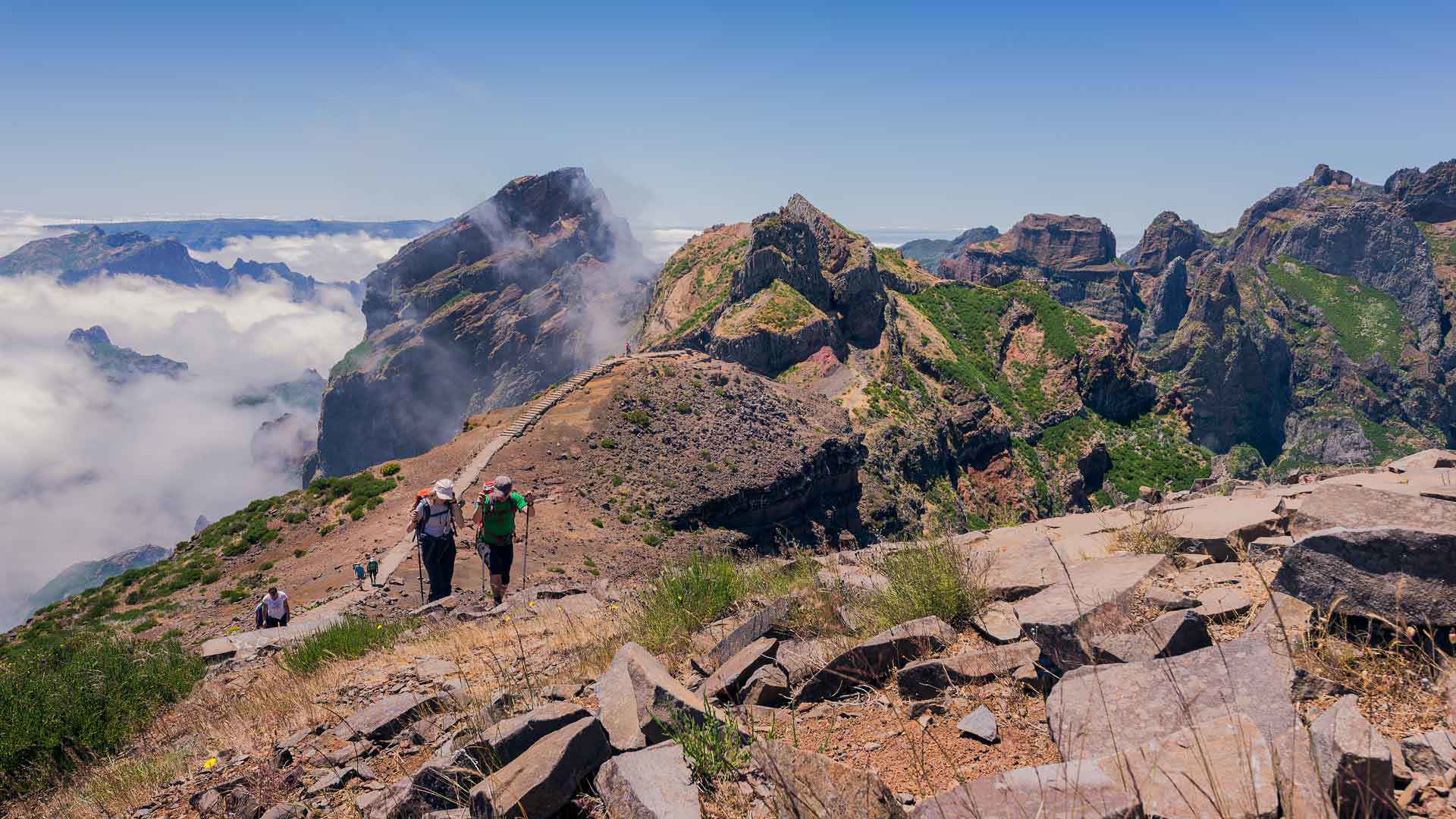 Senderistas recorren un sendero en la montaña con nubes en Madeira.
