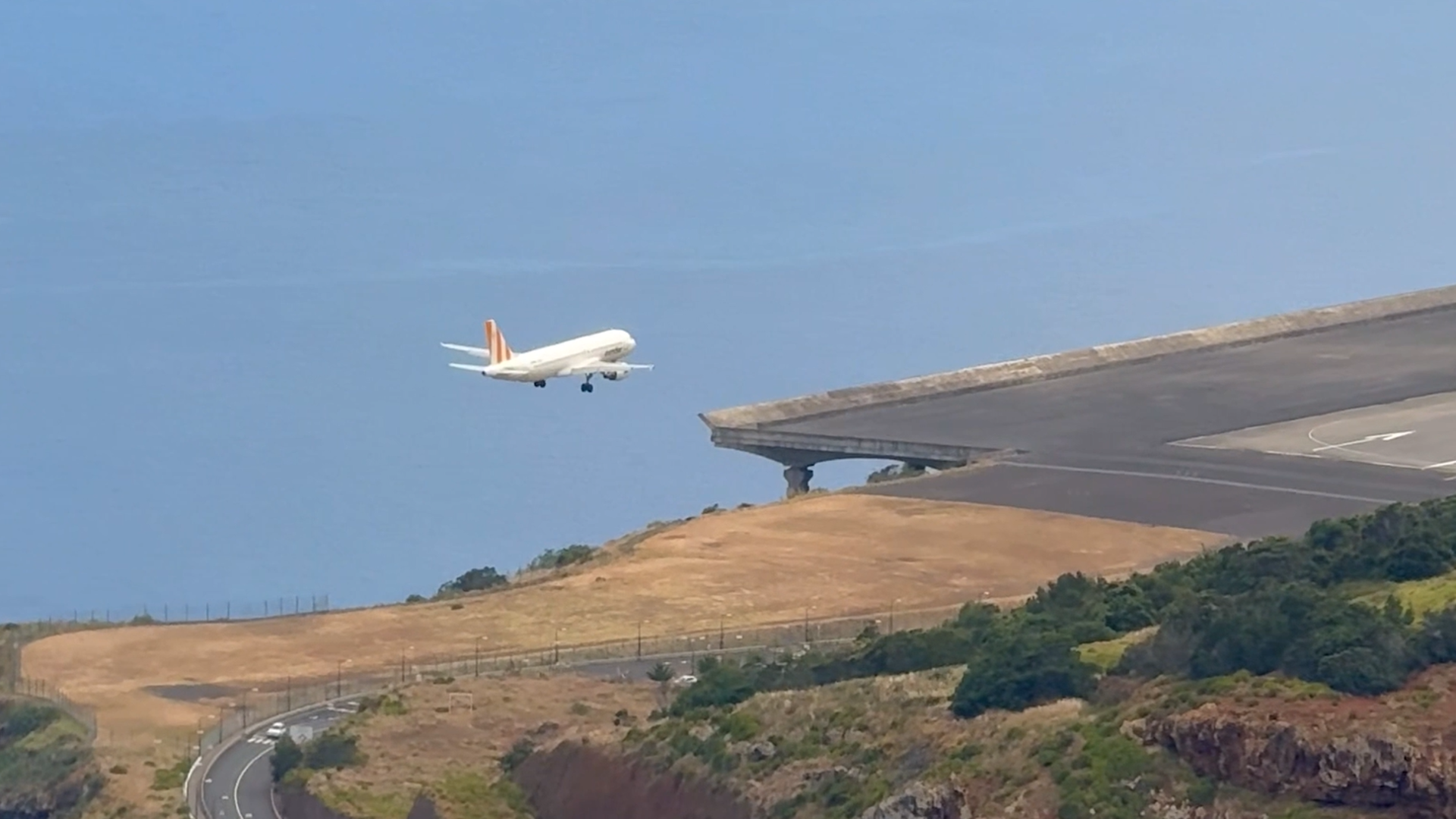 Avião a aterrar no Aeroporto da Madeira, com o mar ao fundo.