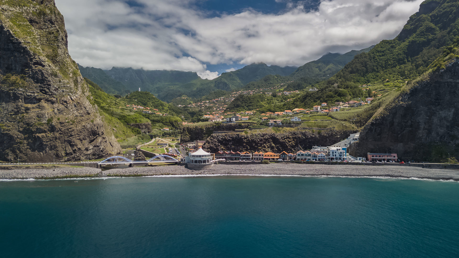 Mar com casas no vale entre nuvens na Madeira.