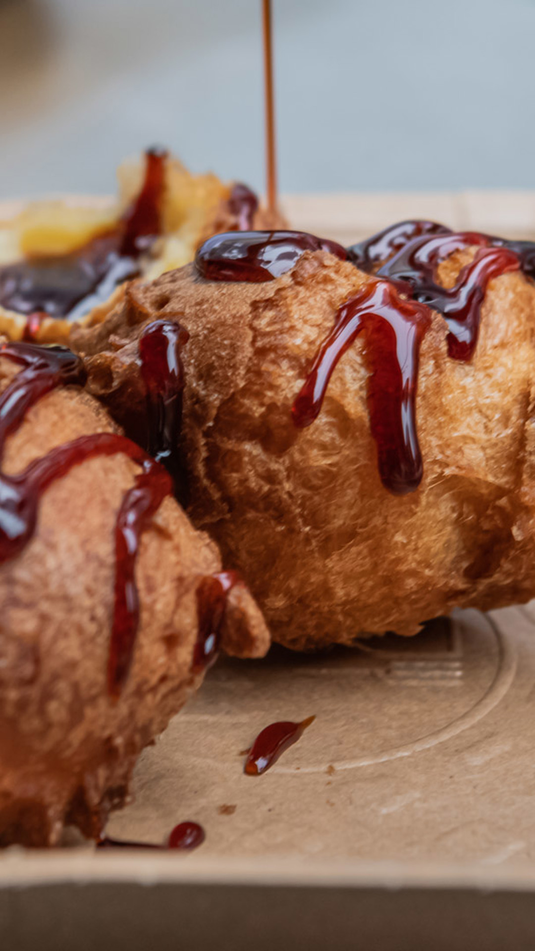 Malassadas servidas num prato com mel de cana por cima.