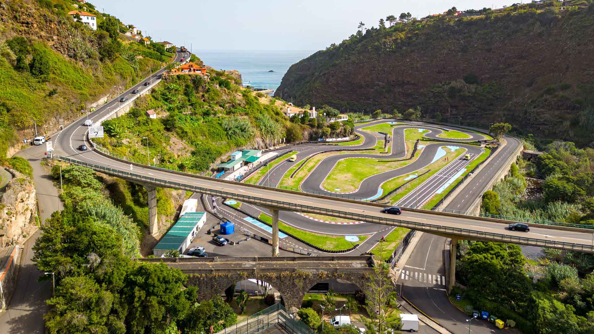 Puente sobre carreteras entre montañas verdes.