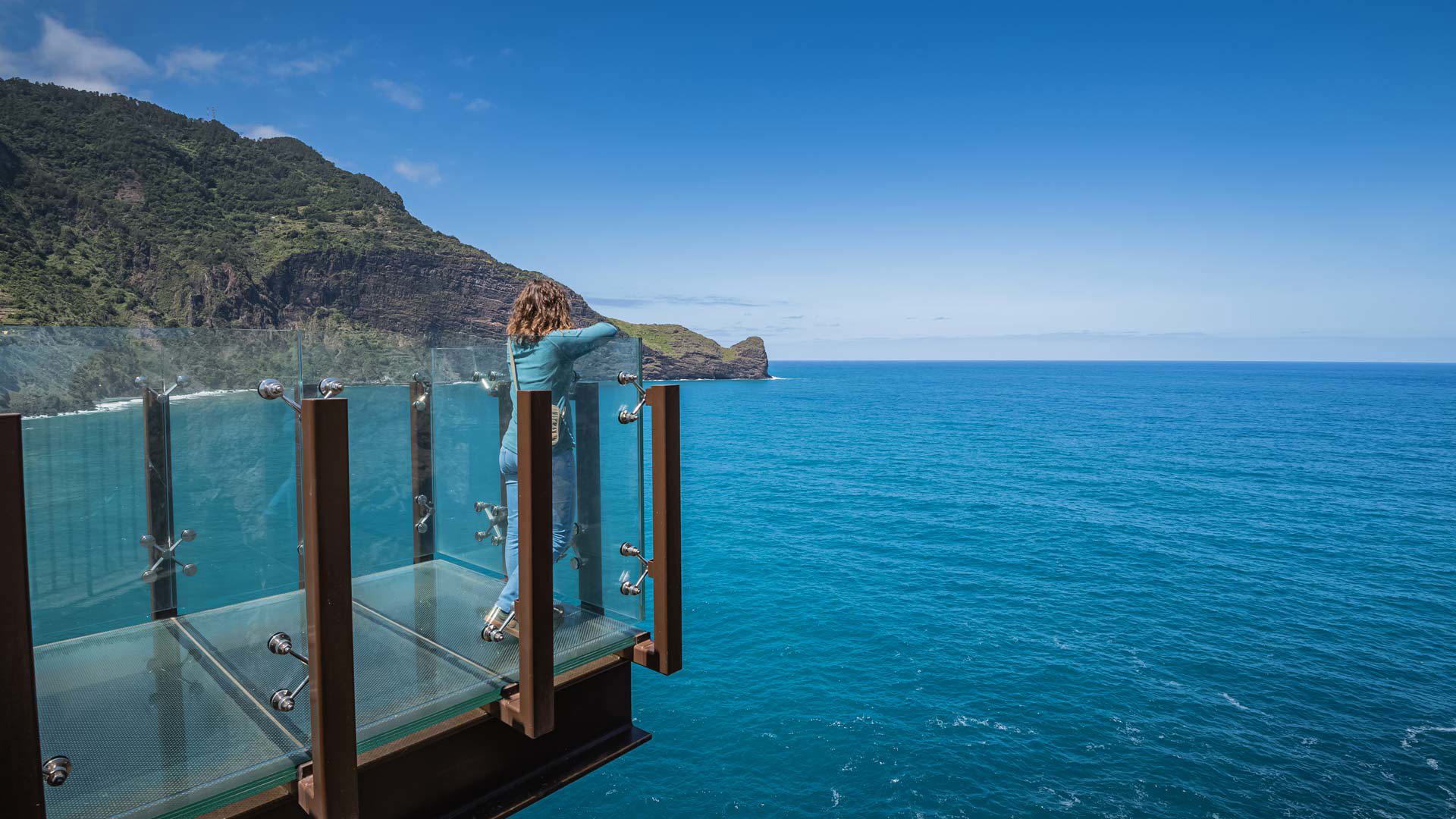 Persona en un mirador de vidrio mirando al mar en Madeira.