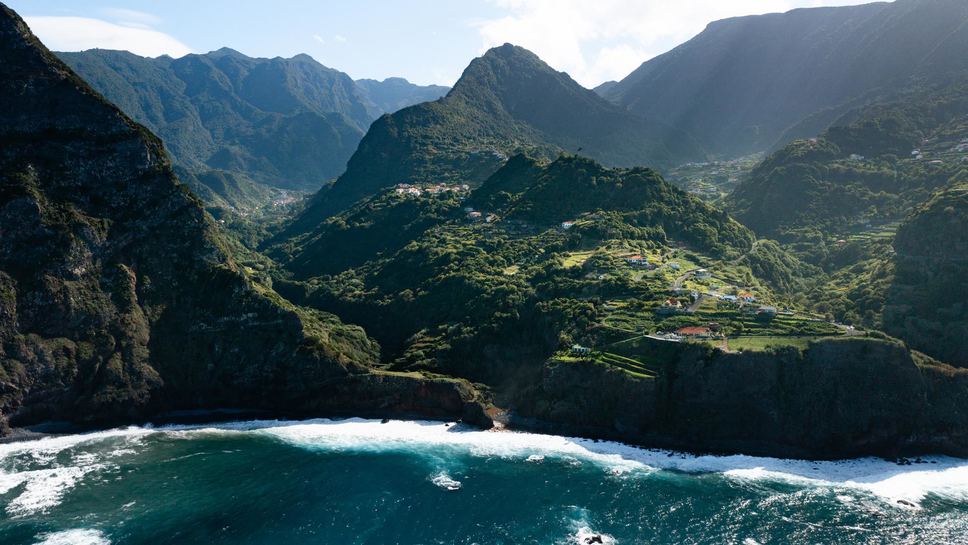 Mar com ondas junto à encosta verde na Madeira.