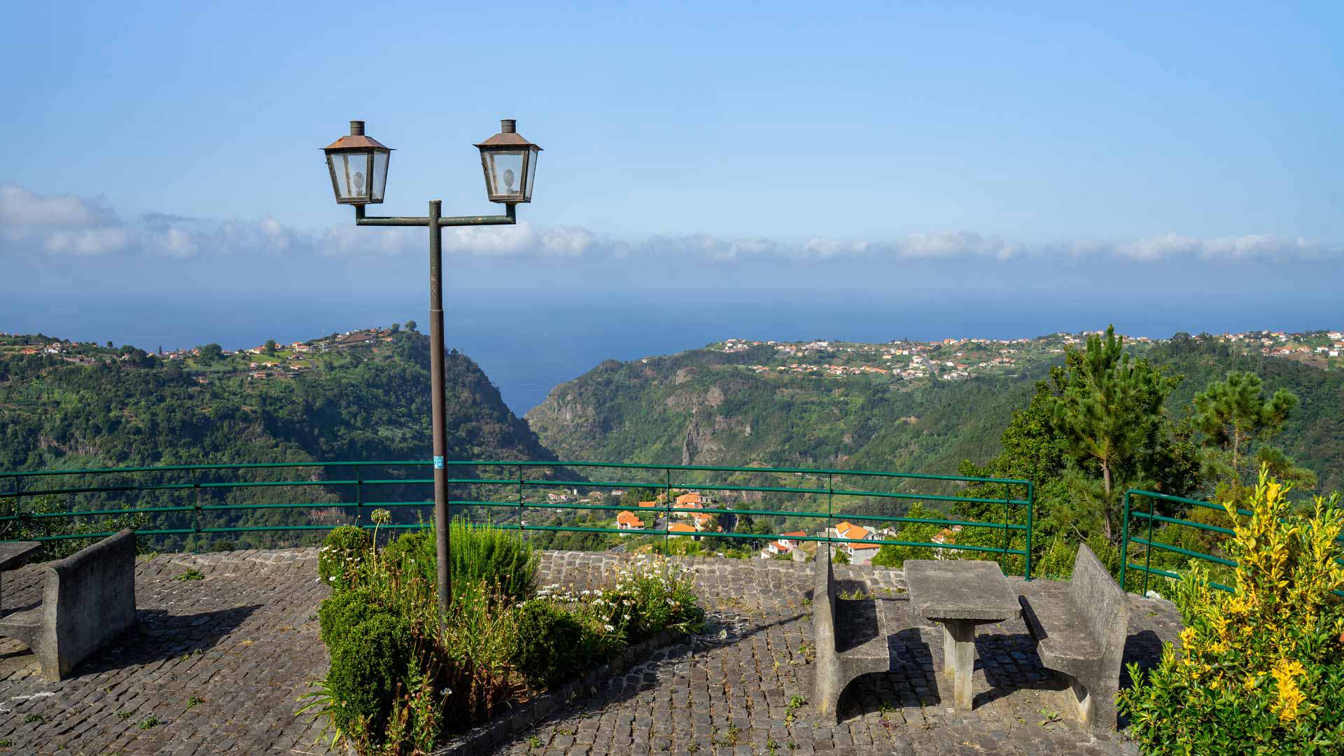 Mirador con bancos de piedra y farola con vistas a montañas en Madeira.