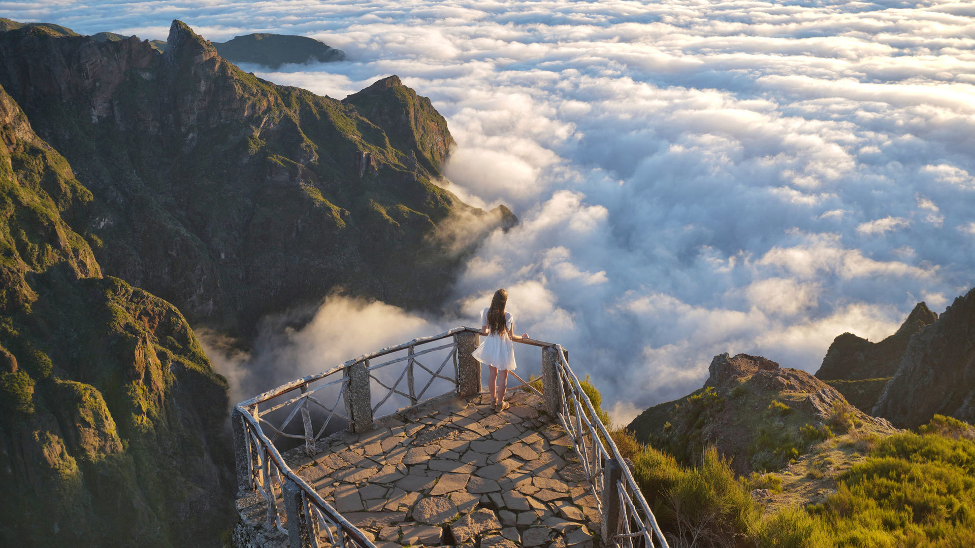 Frau im weißen Kleid an einem Aussichtspunkt mit Wolken im Hintergrund auf Madeira.
