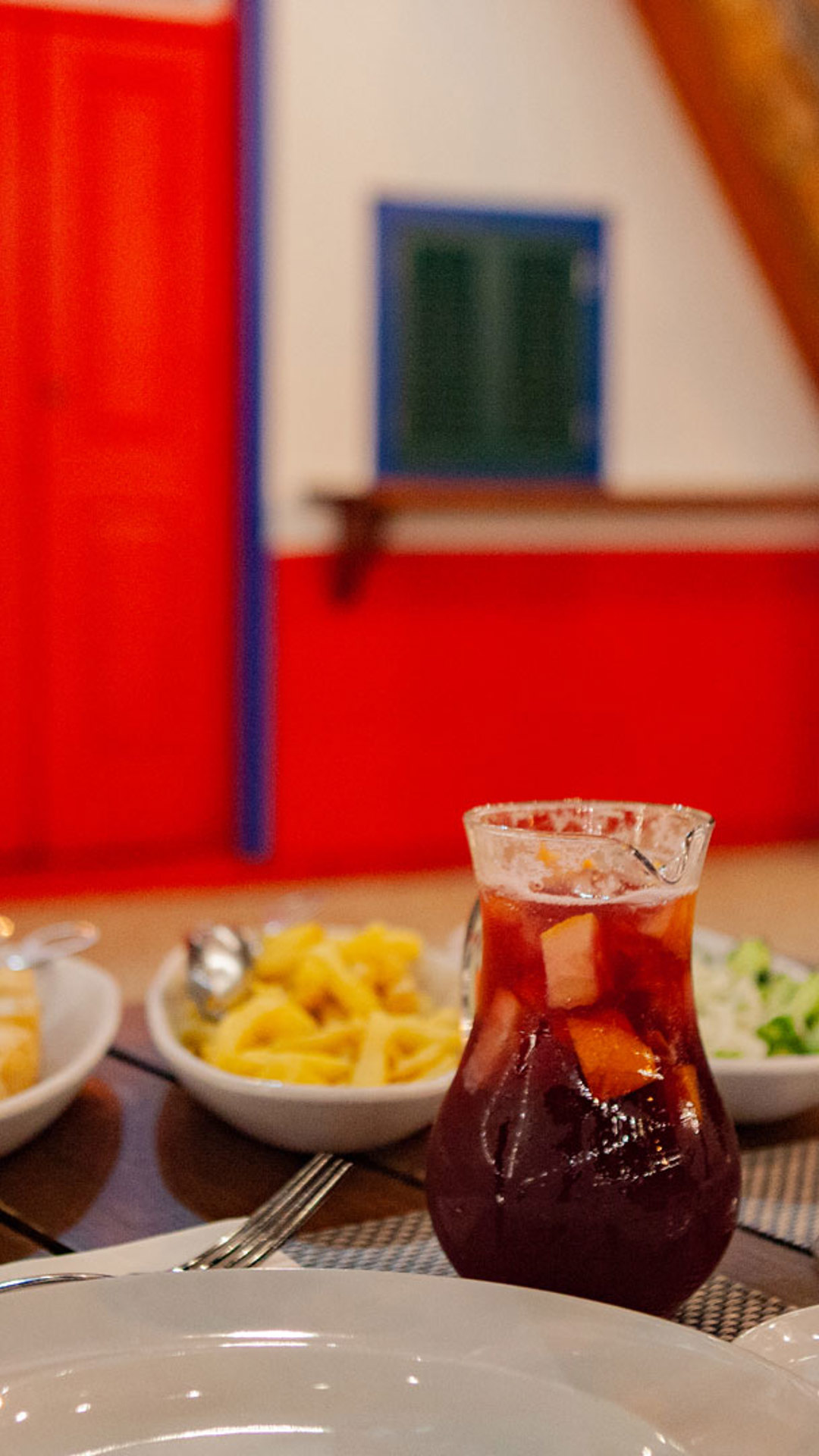 Mesa com comida e jarro de sangria, copos servidos e batata frita.