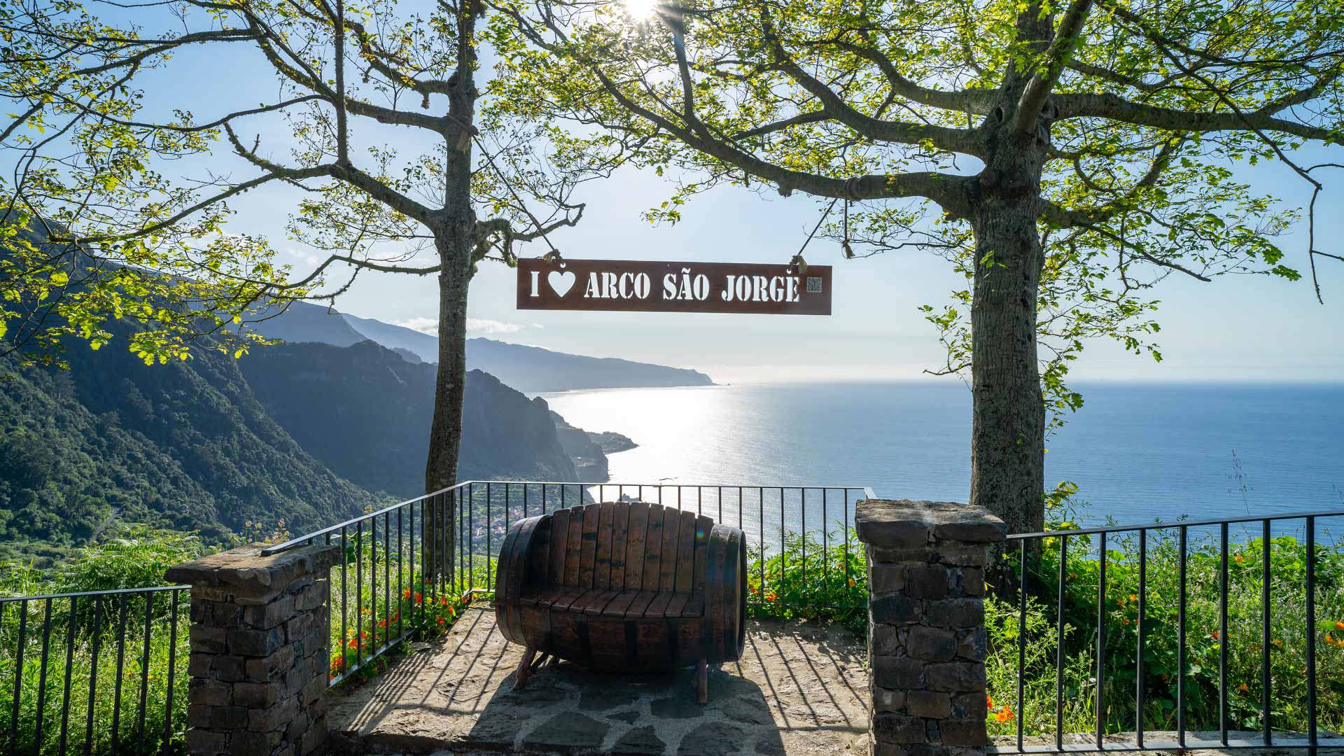 Bank am Aussichtspunkt mit Bäumen, Bergen und Meer auf Madeira.