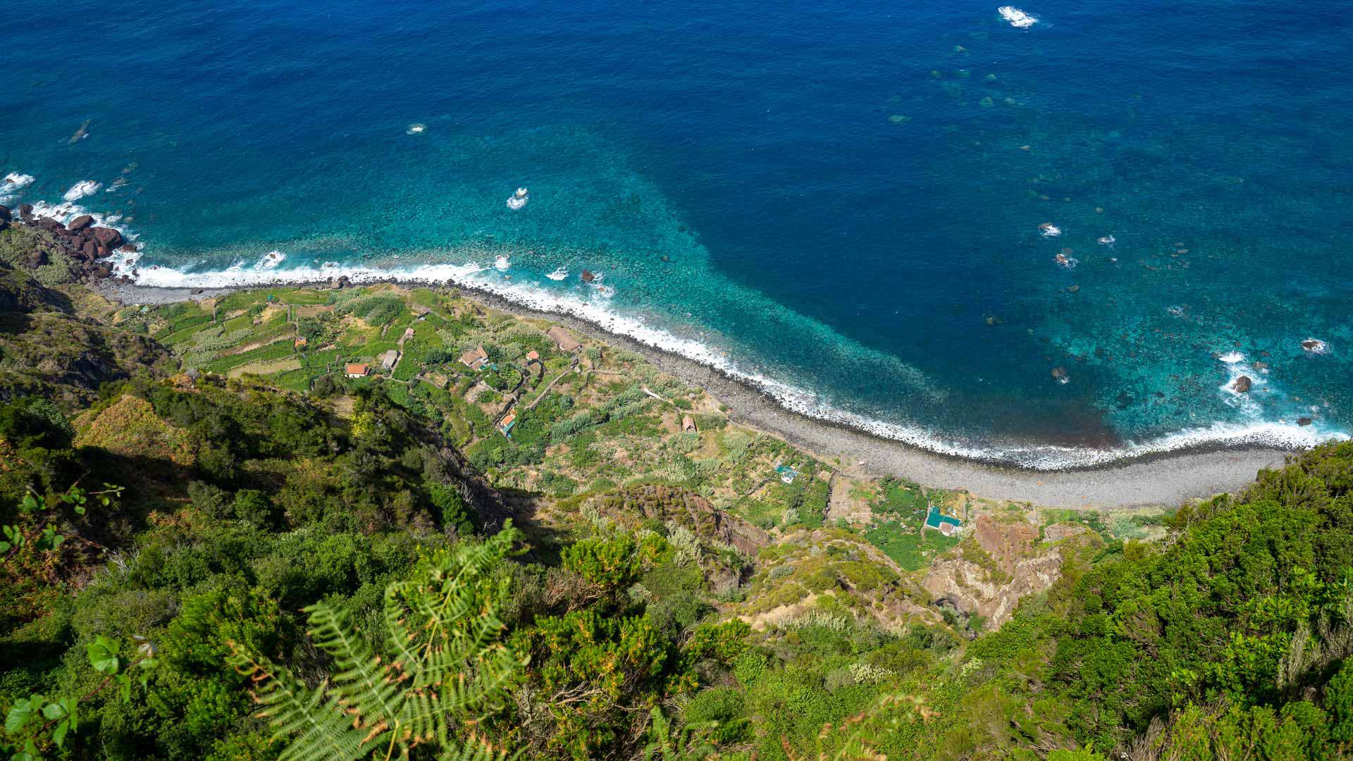 Vegetación verde en terrenos junto al mar y playa de calhau.