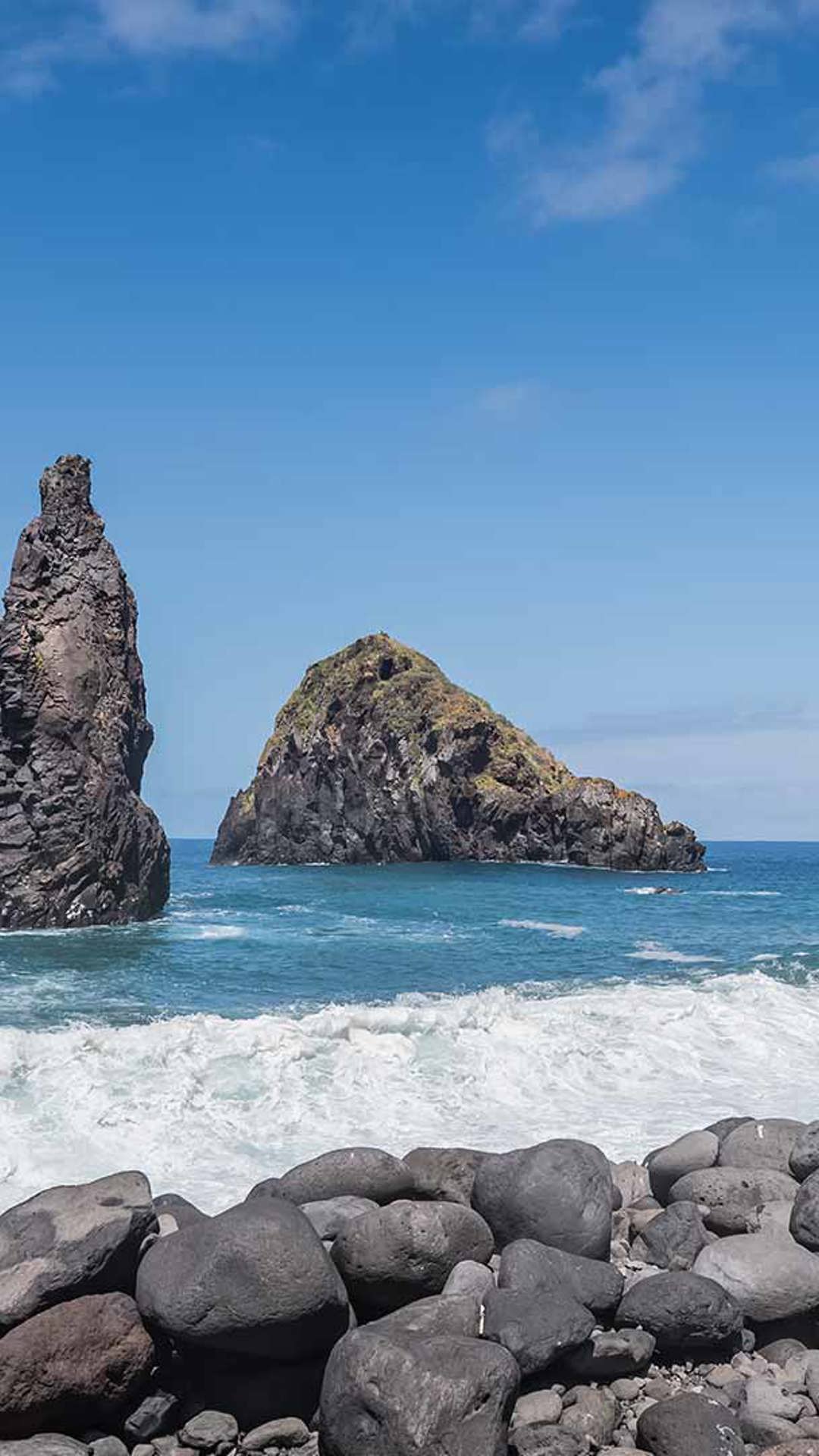 Femme près d’une formation rocheuse et de pierres au bord de la mer à Madère.