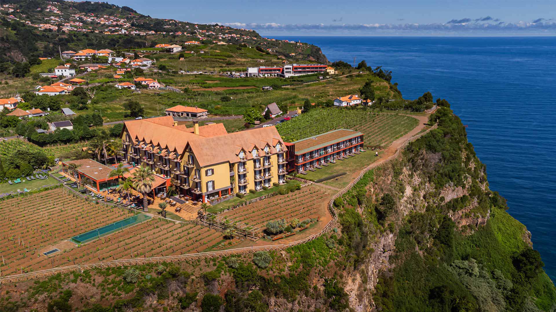 Gelbes Hotel umgeben von Weinbergen mit Meerblick auf Madeira.