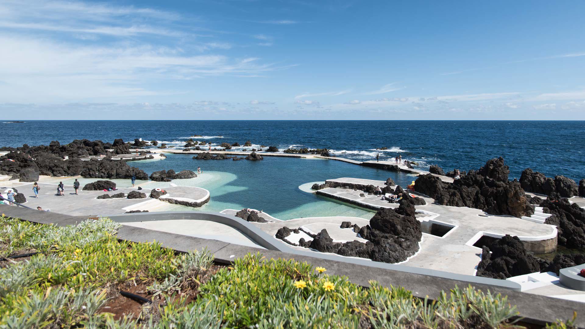 Personnes profitant des piscines naturelles de Porto Moniz, entourées de rochers et de la mer.