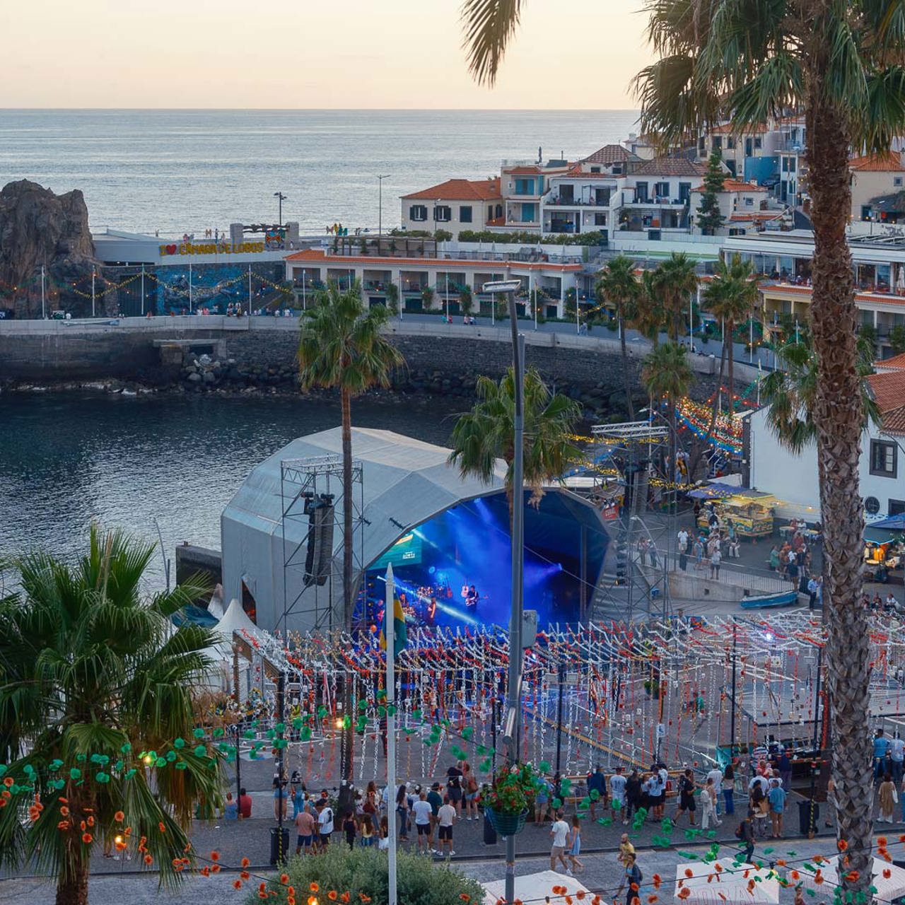 Baie de Câmara de Lobos pendant les festivités, avec scène, animations et vue sur la mer.
