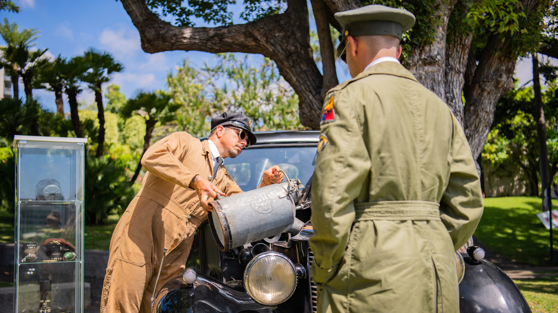 Voiture classique pendant que deux hommes la ravitaillent en carburant.