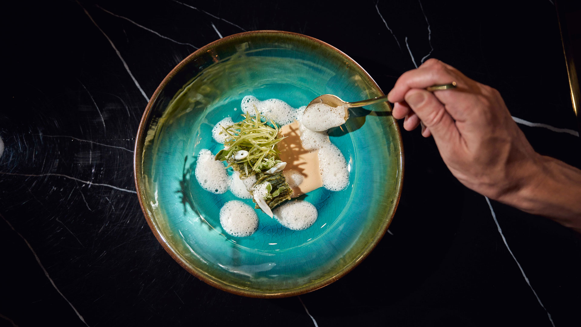 Koch richtet ein farbenfrohes Gericht mit verschiedenen Texturen im Stil der zeitgenössischen Küche an.