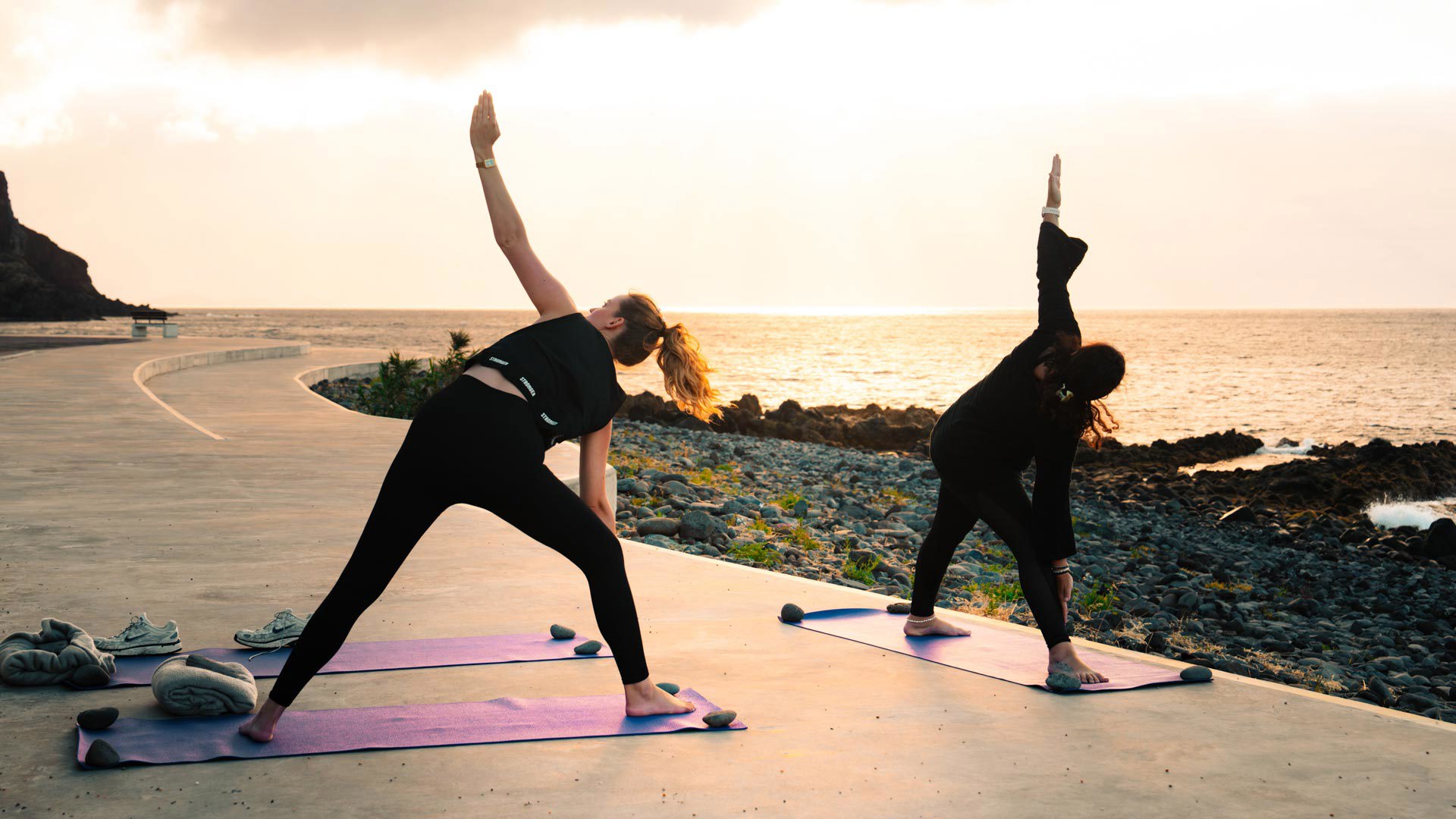 Deux femmes en posture de yoga au bord de la mer.