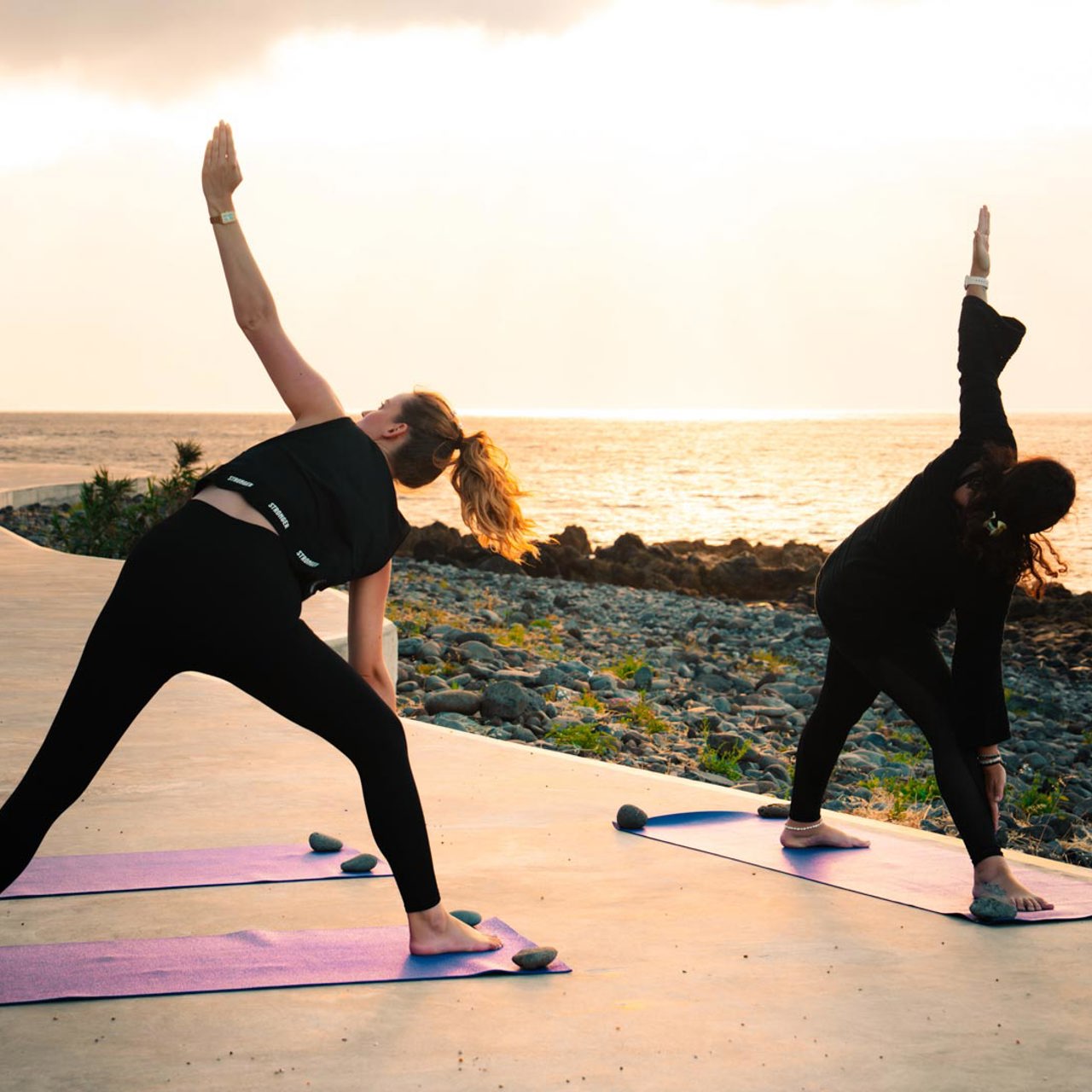 Deux femmes en posture de yoga au bord de la mer.