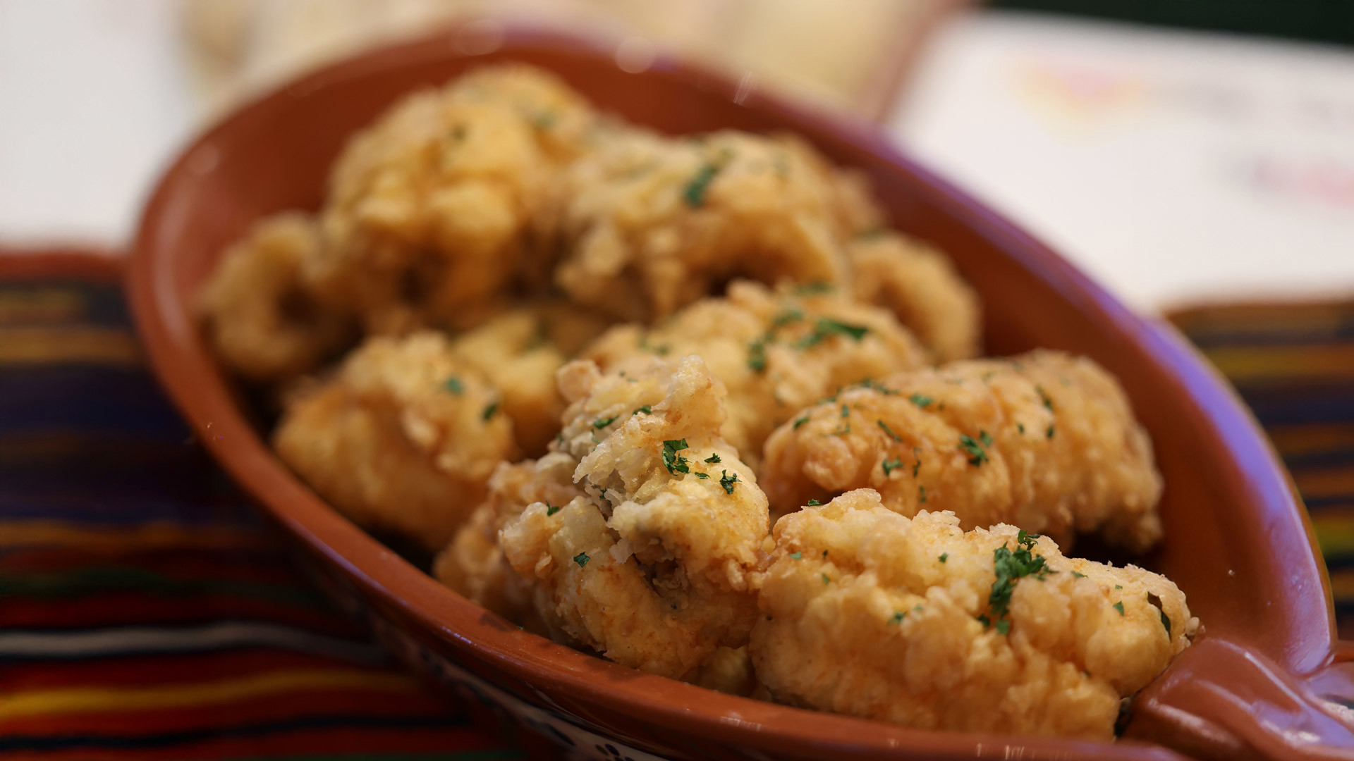 Espada frita servida num prato com salsa por cima.