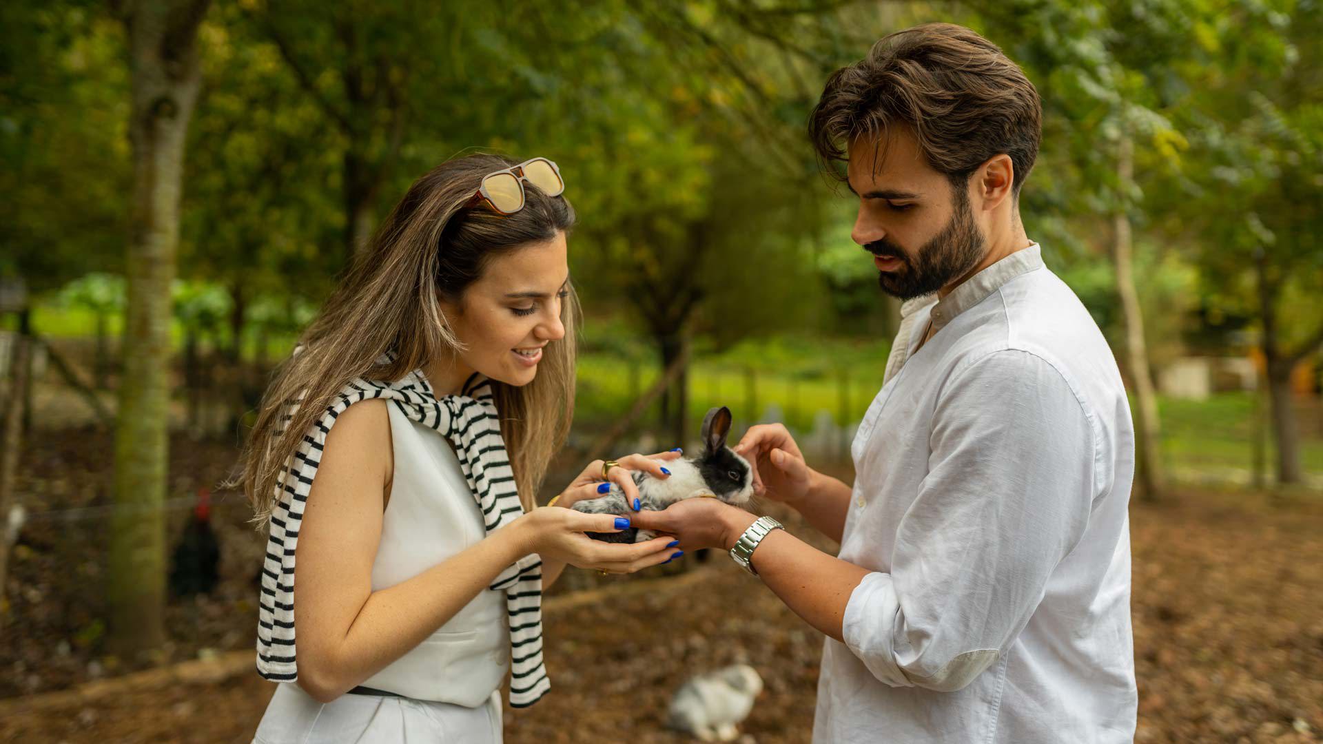 Pareja sujetando un conejo junto a árboles en Madeira.