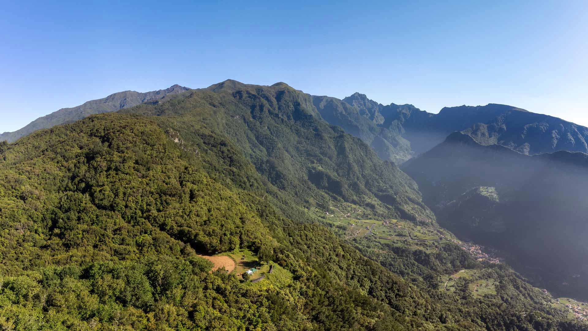 Grüne Berge unter klarem Himmel auf Madeira.