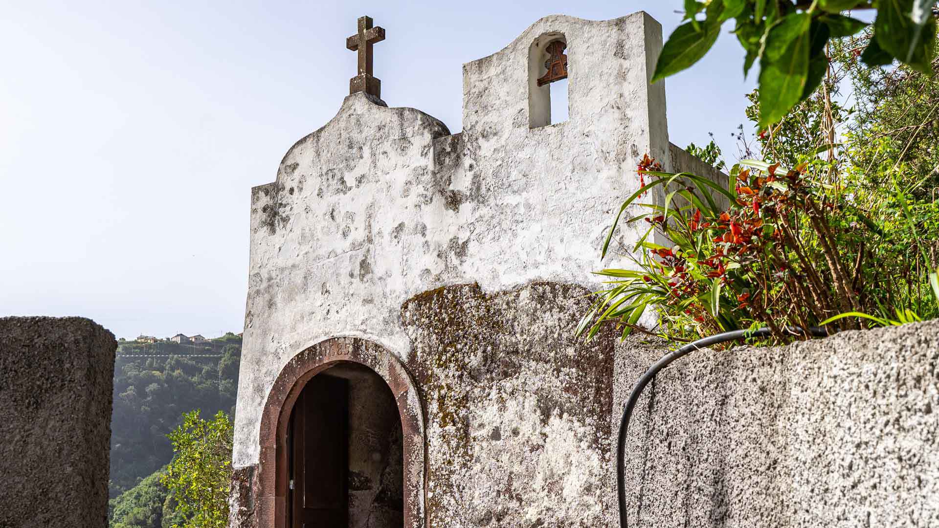 Capilla antigua con flores rojas y plantas.