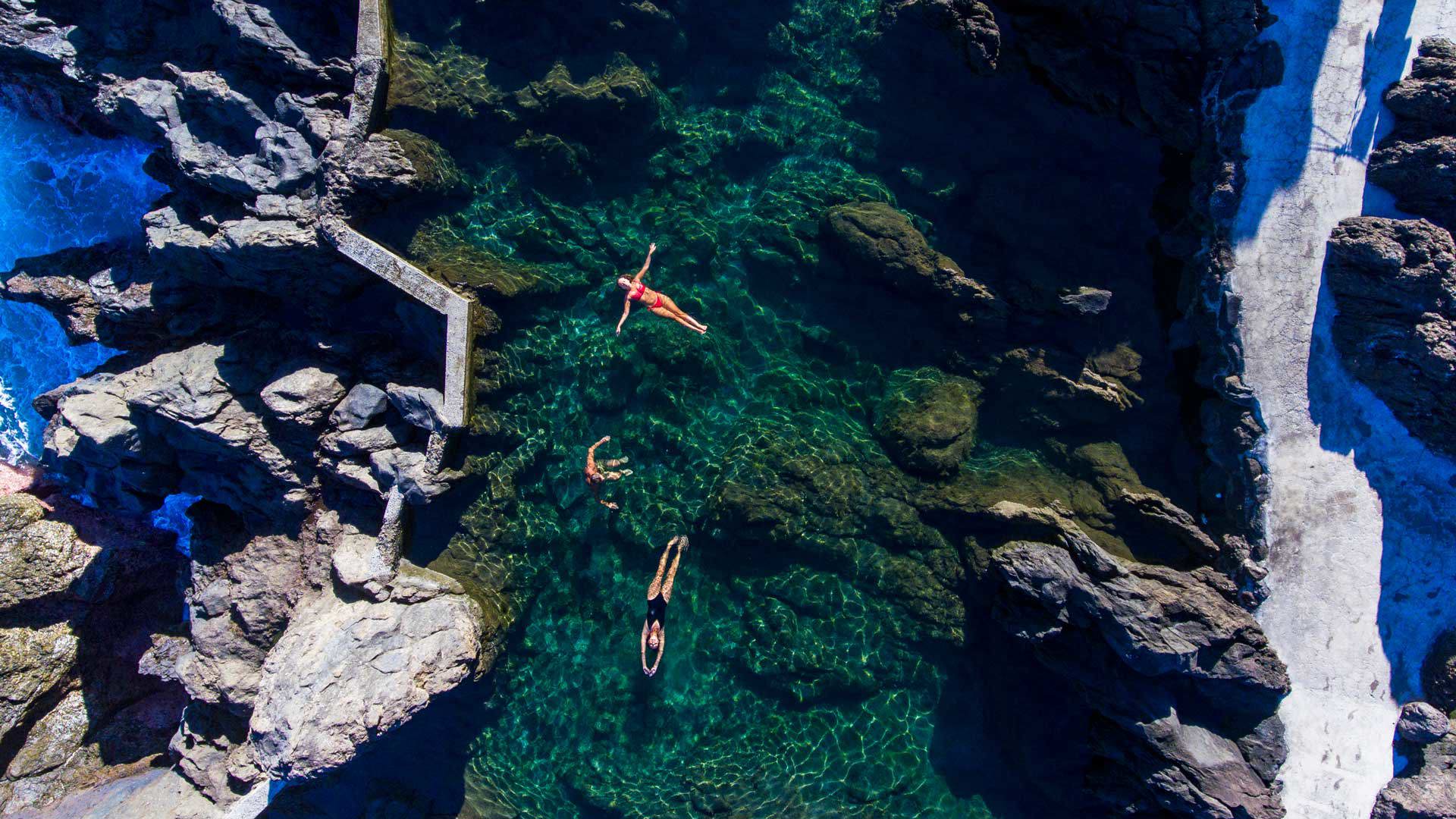 Três pessoas a flutuar nas piscinas naturais do Aquário, Porto Moniz.