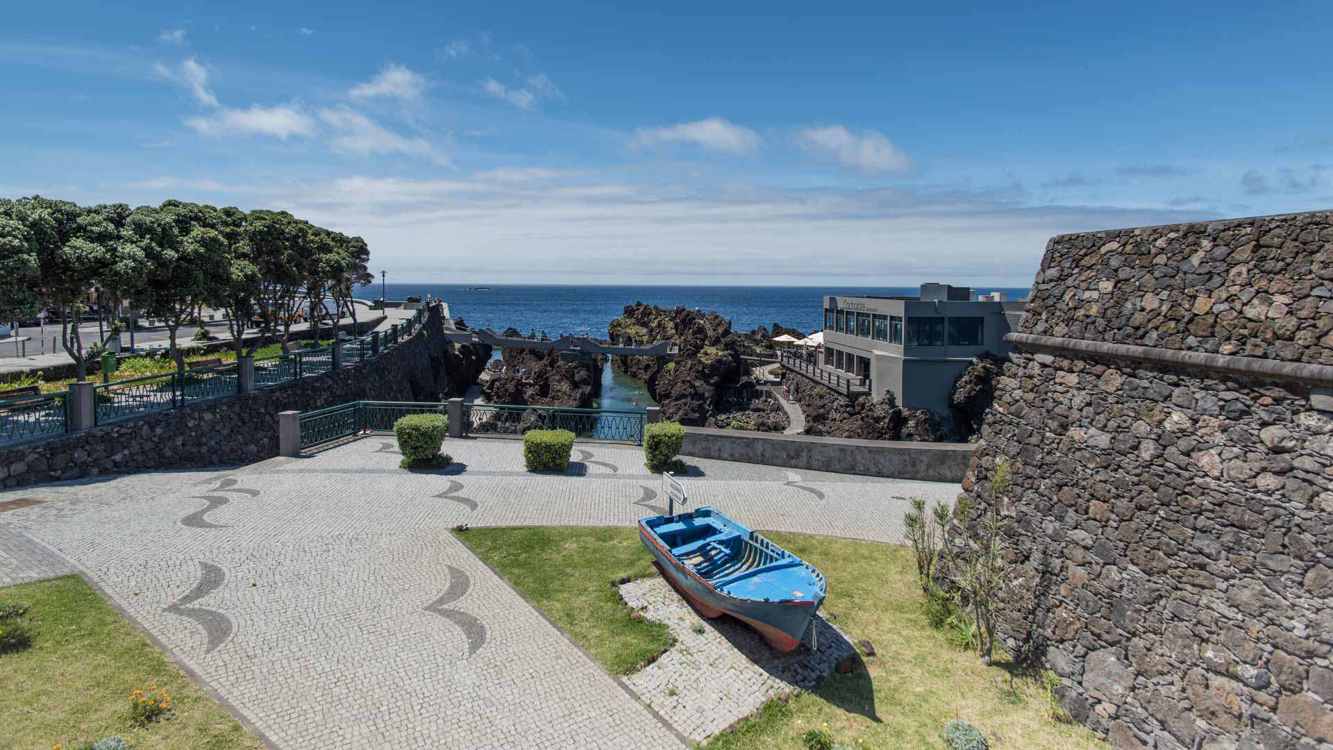 Construcción de piedra junto a barco de madera con paisaje marino.
