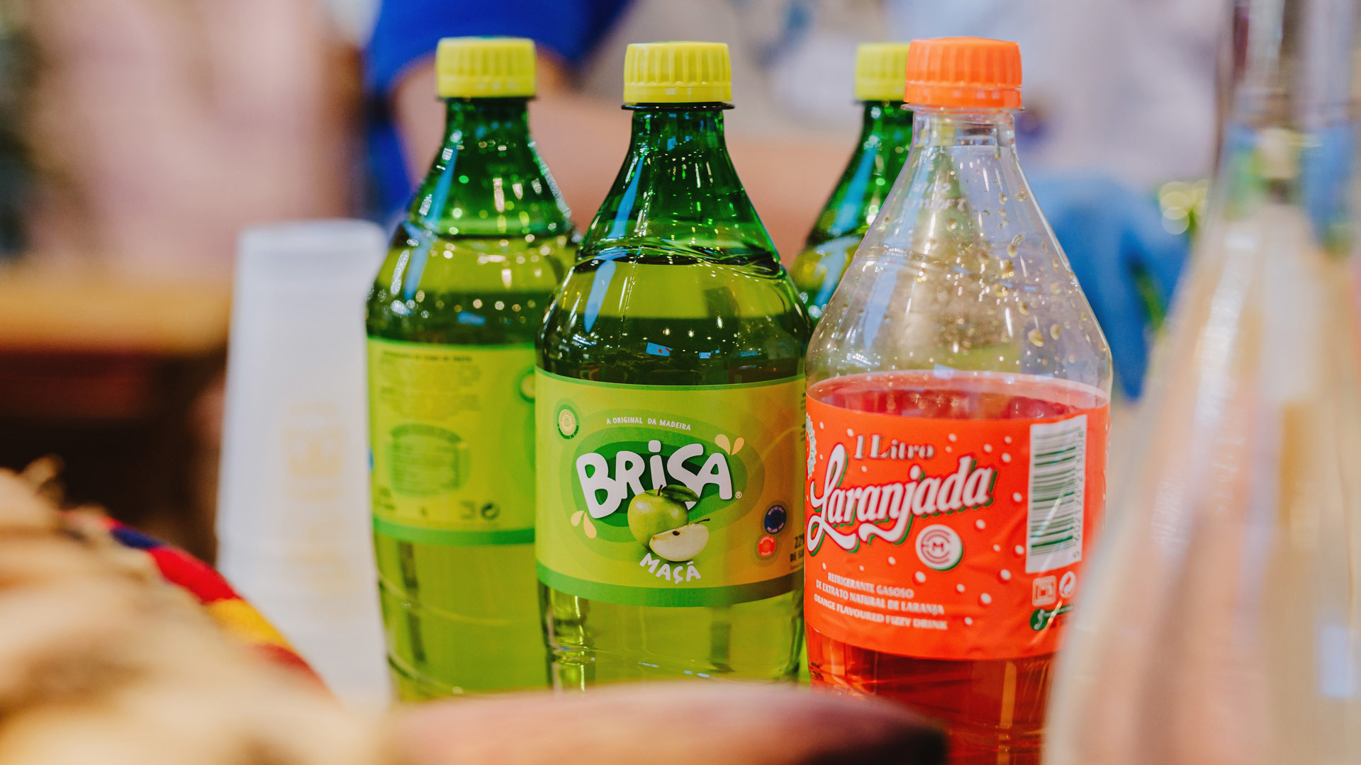 Dos botellas de Brisa manzana, una de naranjada y vasos sobre la mes