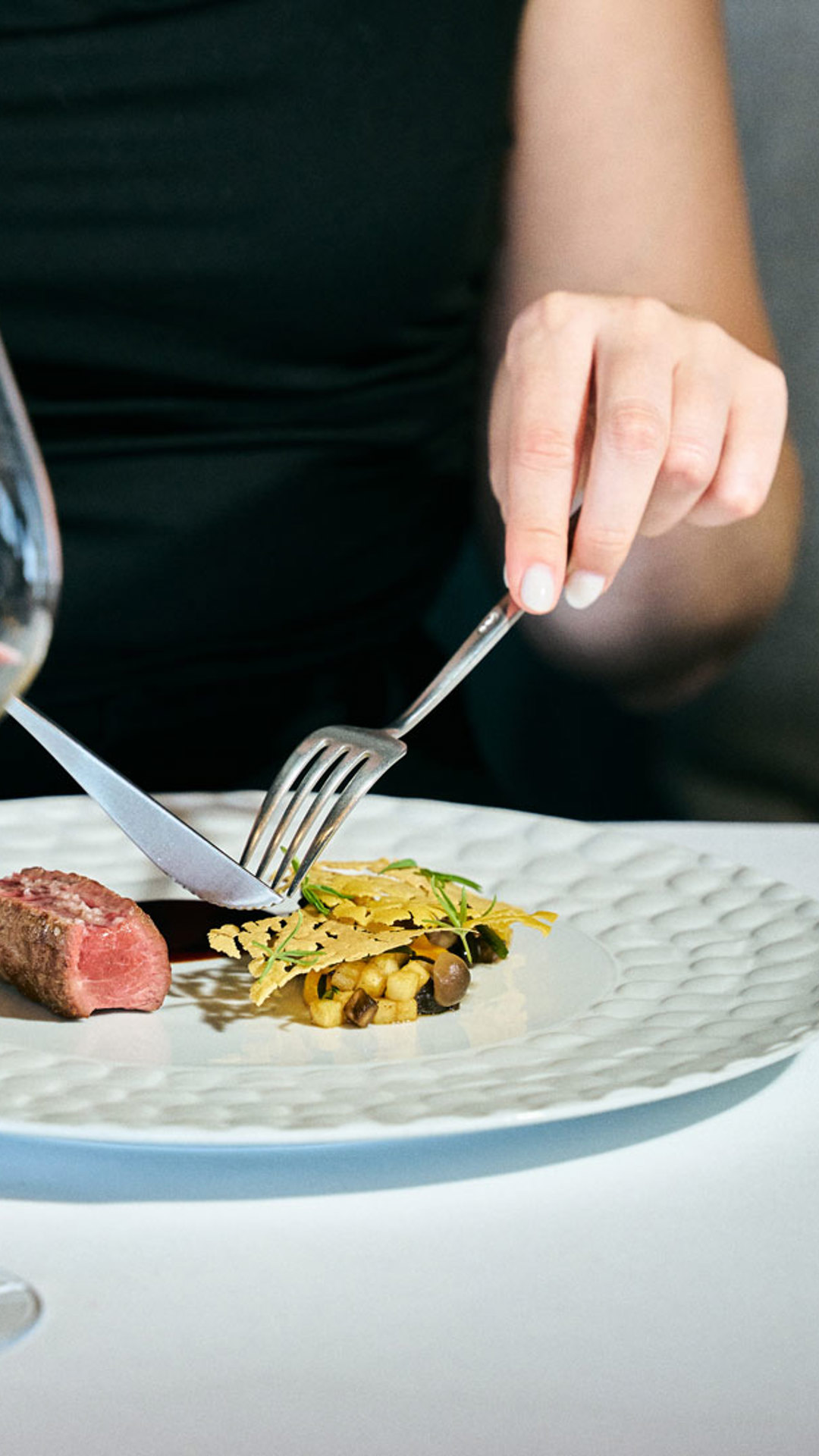 Woman enjoying a contemporary dining experience with a glass of wine in Madeira.