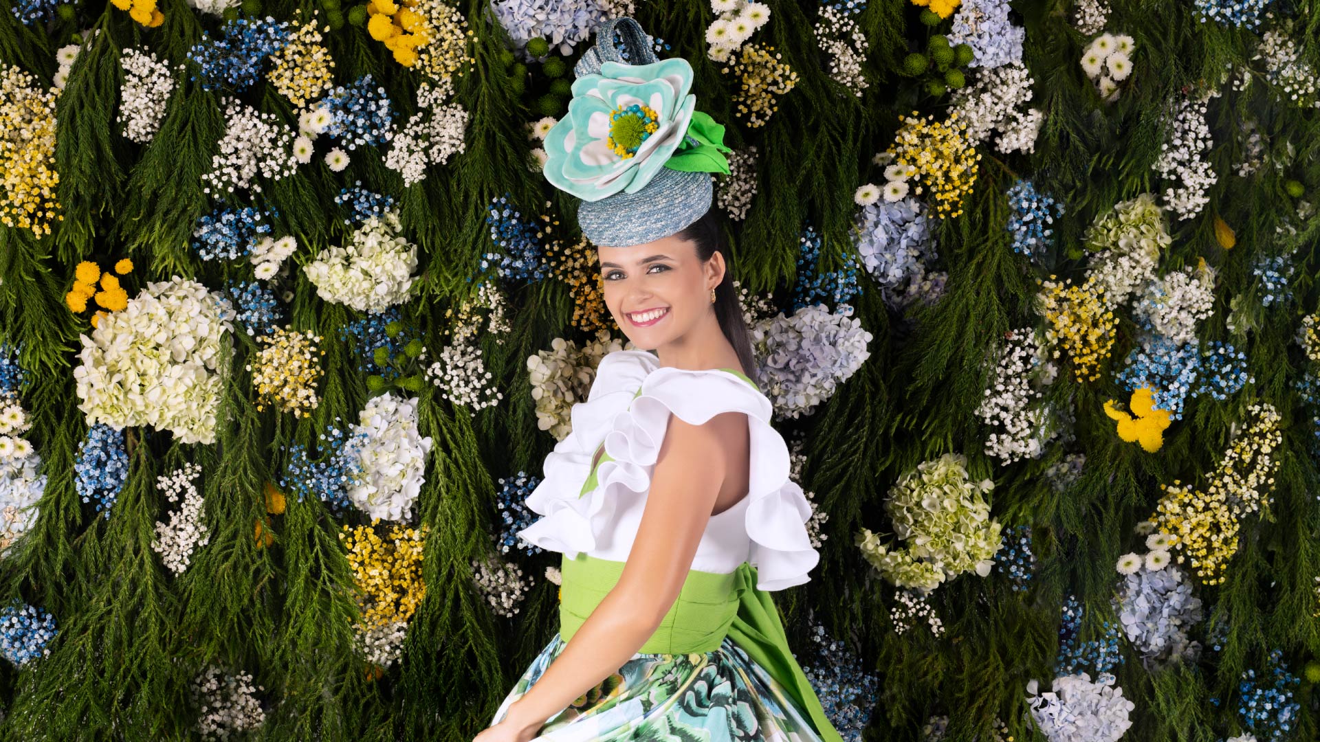 Femme avec une fleur dans les cheveux près d’un mur de fleurs