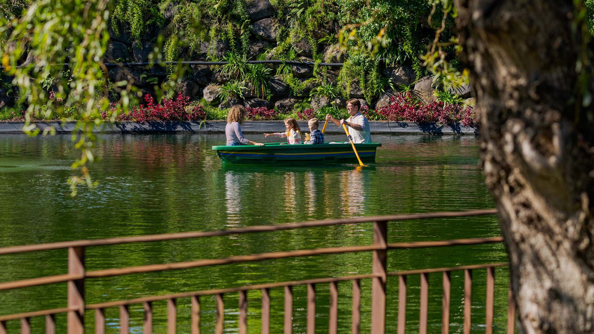 Familia en bote de remos en un lago junto a árboles en Madeira.