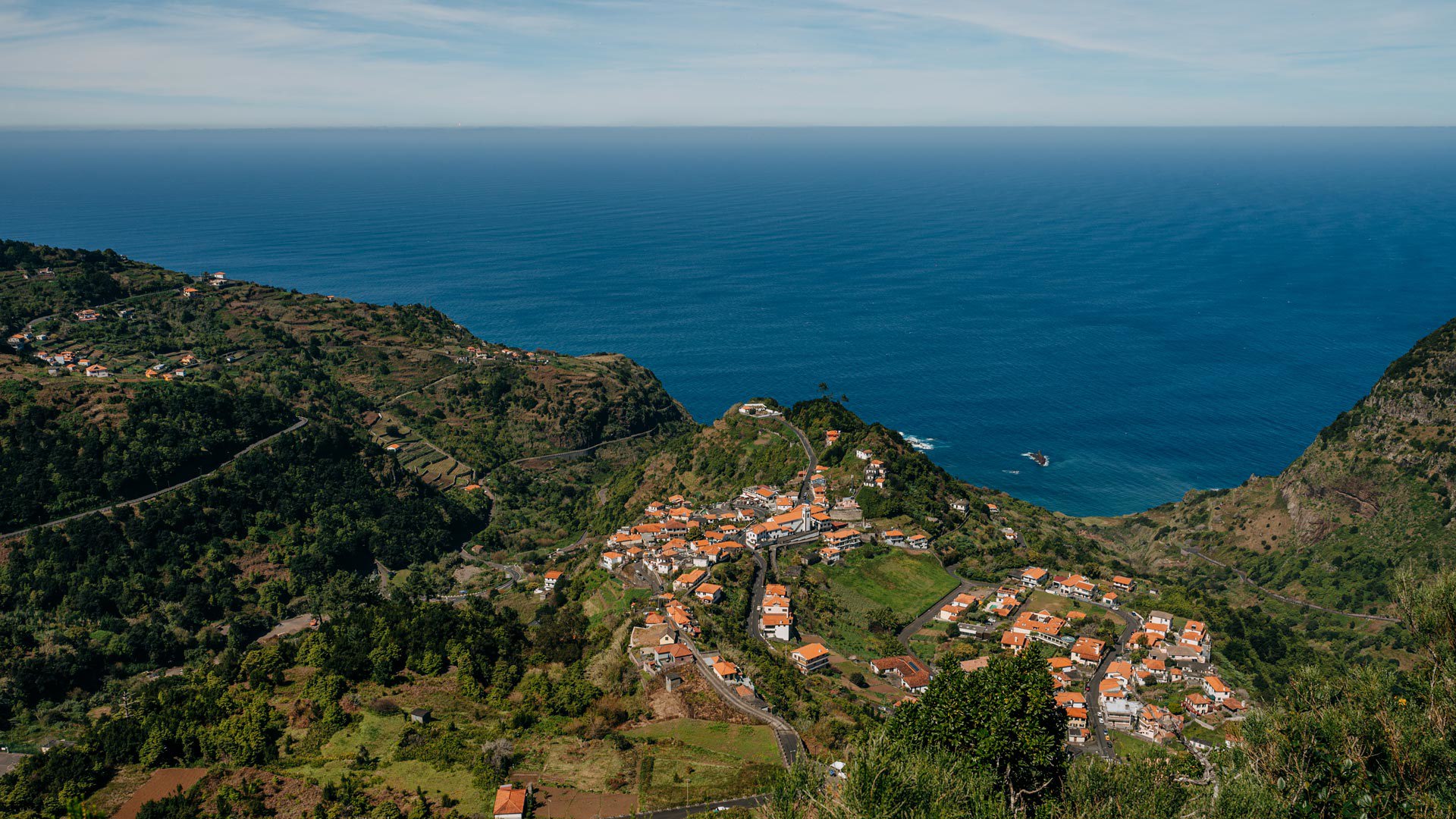 Encosta verde com casas junto ao mar na Madeira.